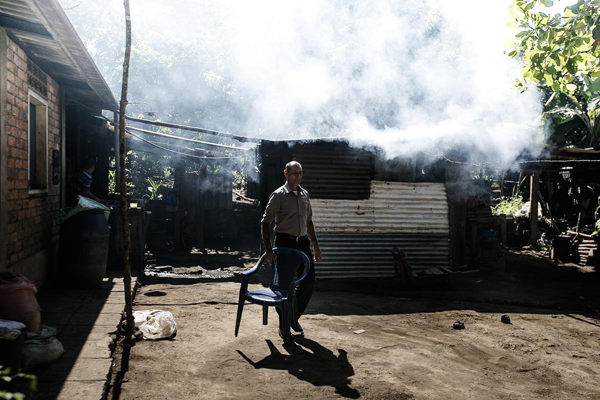 Francisco Arévalo saca una silla para sentarse un momento afuera de su casa en el municipio de San Isidro, Izalco. Foto : Fred Ramos