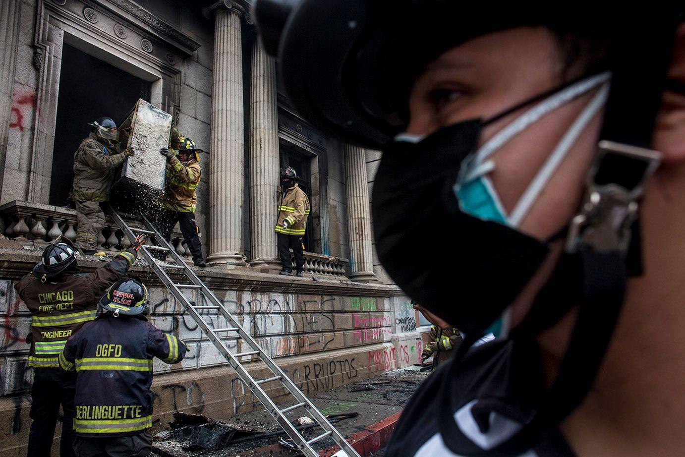 Volunteer firefighters remove burned debris by a congressional window.