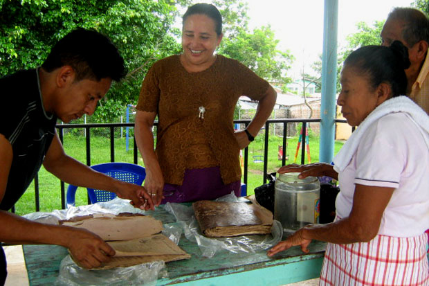 Hilda Valladares, mayordoma (en el centro), y Pedrina Hernández (al costado derecho), cabecilla o capitana, muestran el libro de cuentas de la cofradía, que data del siglo XVII. Foto Elena Salamanca ﻿" /></div> <figcaption class=