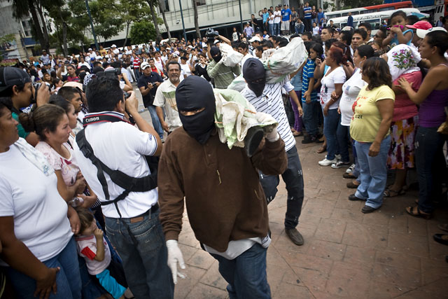 Miembros de las dos principales pandillas del país descargan sacos llenos de armas en la plaza Barrios. Foto Pau Coll