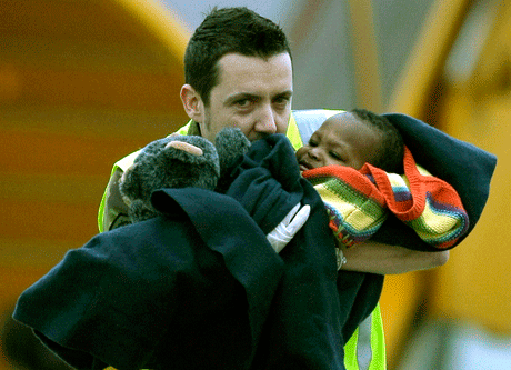 Un miembro de la Real Fuerza Aérea Holandesa carga a un niño haitiano envuelto en un cobertor hasta un autobús tras llegar al aeropuerto de Eindhoven, en el centro de Holanda, el jueves 21 de enero del 2010.