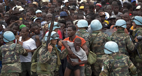 Un integrante uruguayo de las fuerzas de paz de la ONU retira a un niño de una multitud en espera de recibir alimentos en Puerto Príncipe le lunes 25 de enero de 2010