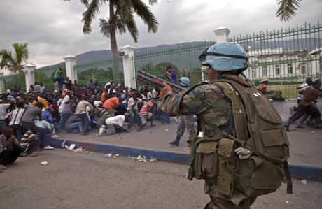 Un integrante uruguayo de las fuerzas de paz de la ONU dispara para dispersar a una multitud que comenzó a saquear los suministros de ayuda en Puerto Príncipe el lunes 25 de enero de 2010.