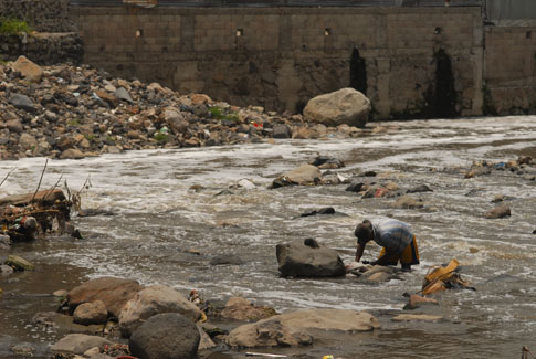 Un minero busca metales para venderlos como material de reciclaje en el agua del río Acelhuate en la comunidad El Coro de San Salvador.