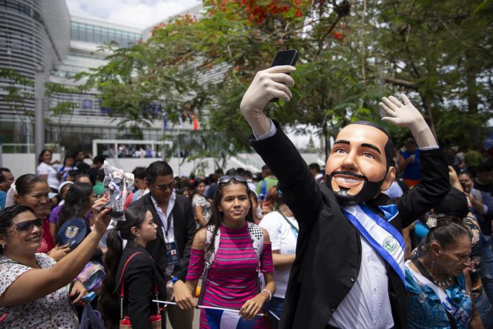 Asistentes a la plaza Barrios se fotografiaron con el personaje de Bukele que otros asistentes interpretaron durante la investidura inconstitucional de Bukele el 1 de junio de 2024. Foto de El Faro: Víctor Peña. 