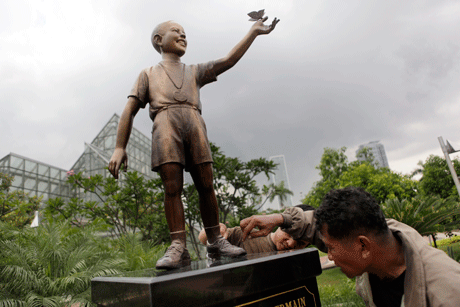 Los trabajadores dan los toques finales a la estatua de bronce del presidente estadounidense Barack Obama de joven, en un parque de Yakarta, Indonesia
