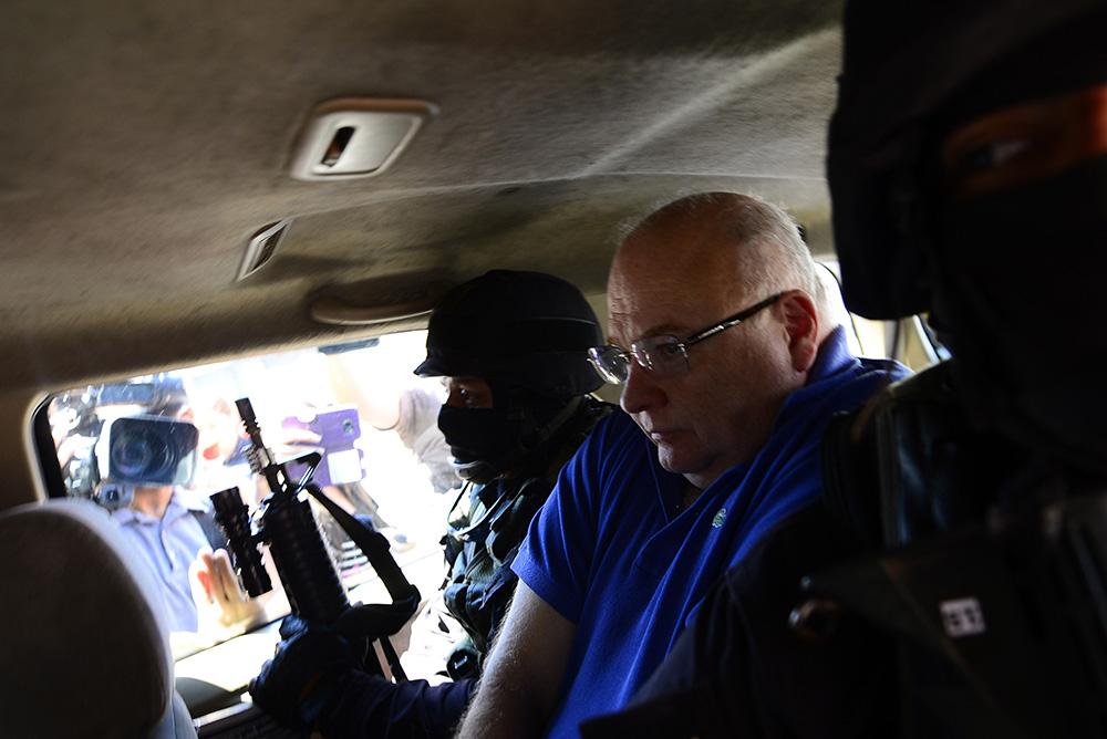 Elmer Charlaix , exsecretario privado, custodiado por dos policías en una foto de archivo de octubre de 2016, cuando fue capturado por su rol en el esquema de corrupción del gobierno de Antonio Saca. Foto: Marvin Recinos (AFP).