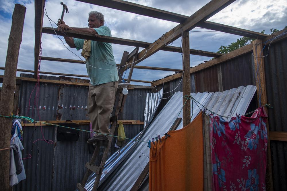 Jose Portillo builds the roof of his home. While constructing his house he had to sleep under sheets of aluminum in order to stay dry. It rained almost every night for a week before he finished his roof.