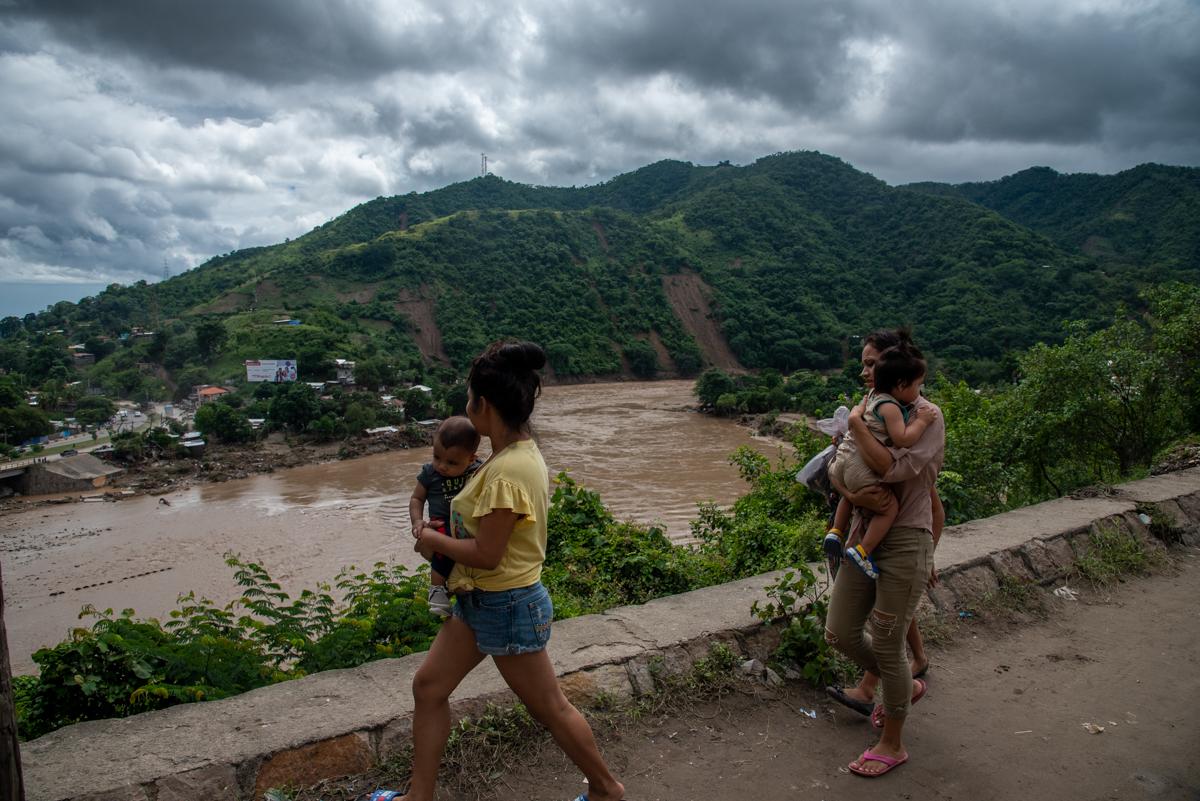 A recently displaced family walks past the Chamelecon River, which flooded and destroyed their home. Flooding in the aftermath of Hurricane Eta has displaced hundreds of thousands in Honduras. There are many missing people, and the death toll is expected to rise.