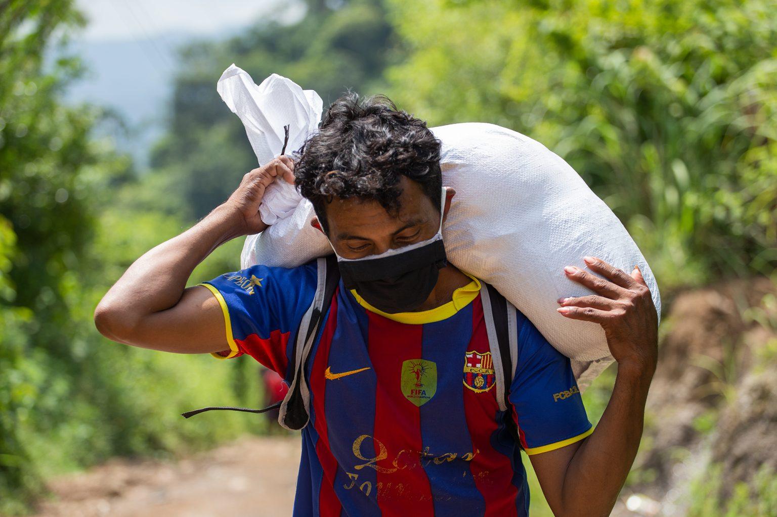 A young man carries a sack of food handed out by the Red Cross. To reach his community, the young man will have to walk at least half an hour with this sack on his back. Curarén, Francisco Morazán, August 27 2020. Photo: Martín Cálix