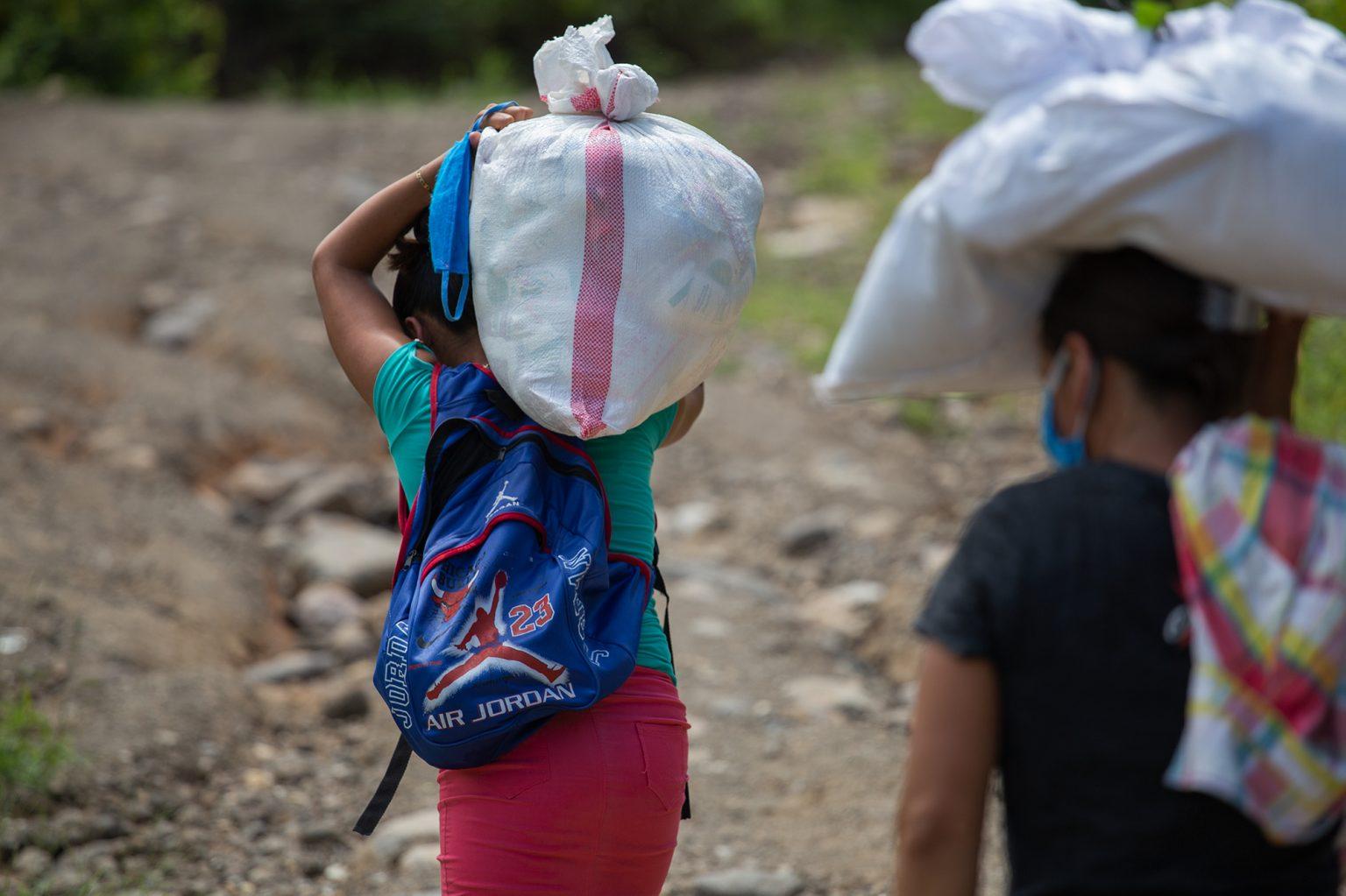 Two women who have divided the load walk to their homes, located at least an hour from the drop off location. This help – although small – will help feed their families for at least 15 days. Aguanqueterique, La Paz, August 29 2020. Photo: Martín Cálix