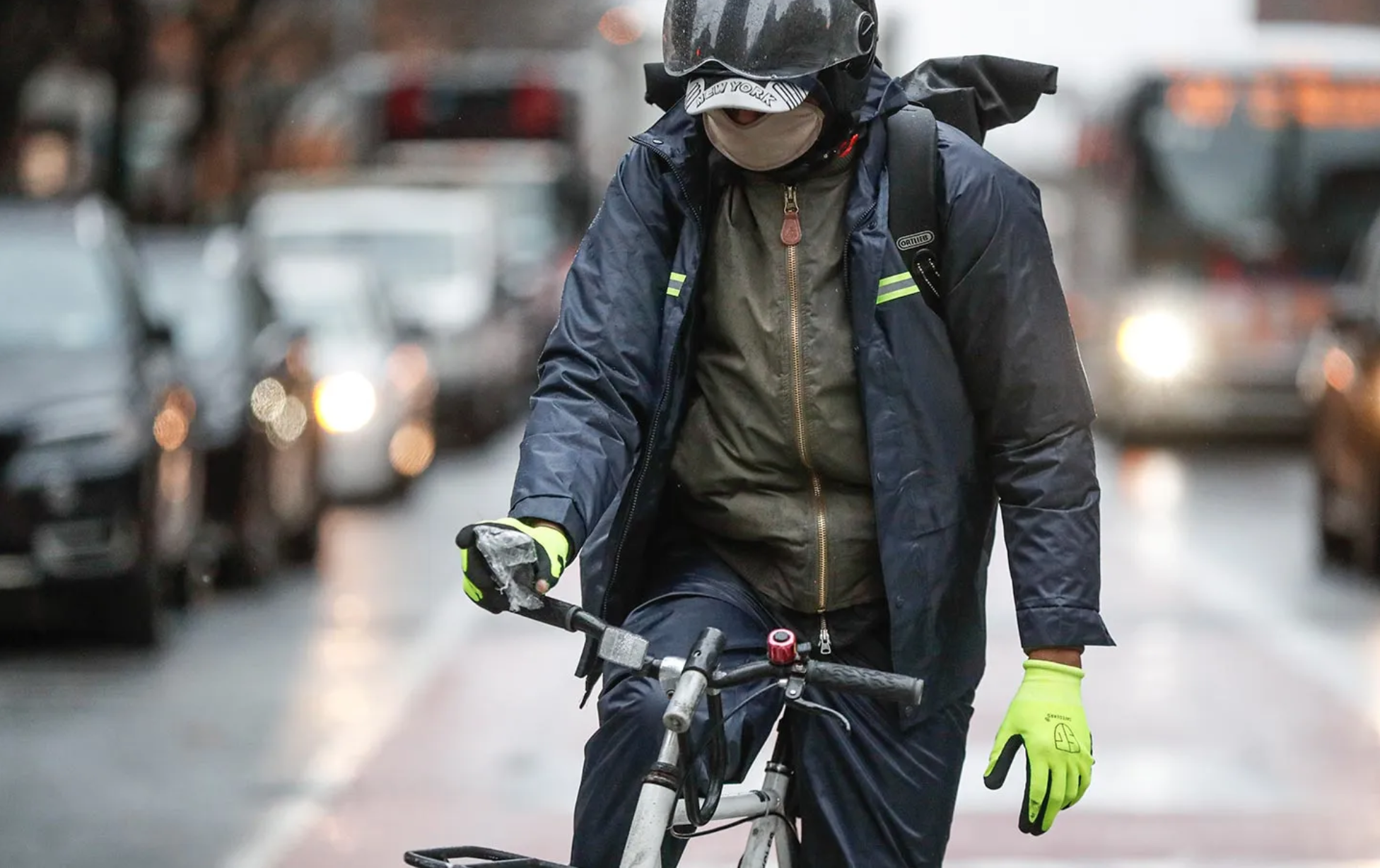 A delivery worker wears protective gloves and a face mask as he rides through traffic, March 23, 2020, in New York. (John Minchillo / AP Photo)