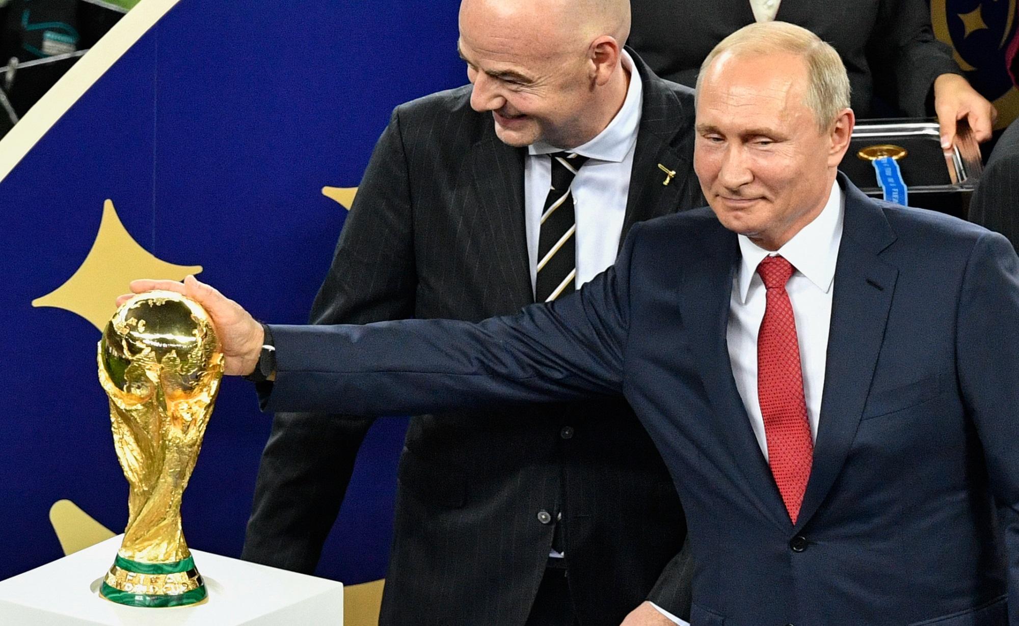 Vladimir Putin acaricia el trofeo de la Copa Mundial de la FIFA. Detrás, Gianni Infantino le ríe la gracia. Foto Alexander Nemenov (AFP).