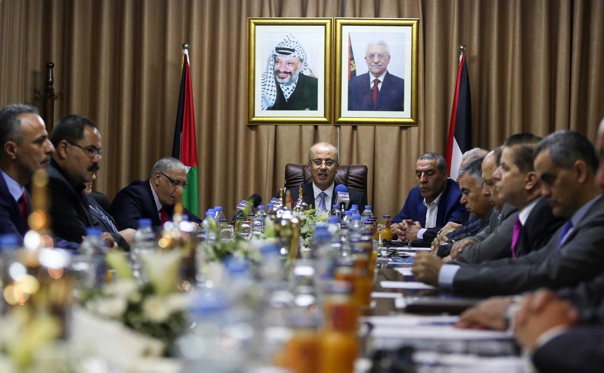 El primer ministro palestino, Rami Hamdalá, preside la reunión del gobierno en Gaza, la primera vez en tres años, bajo los retratos de Yaser Arafat y de Mahmud Abas. Foto Mohammed Abed (AFP).