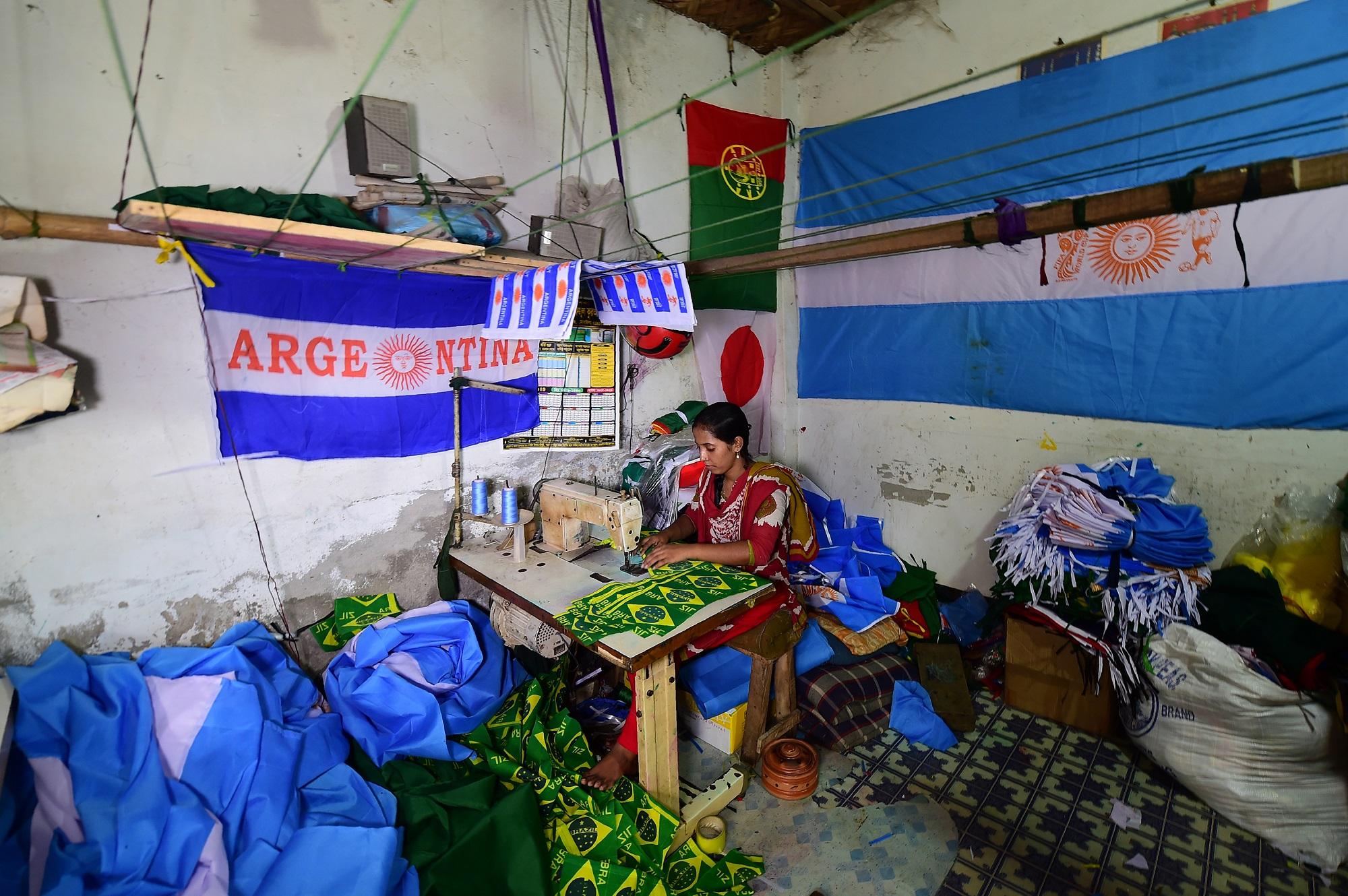 Una mujer bangladesí trabaja confeccionando banderas de Brasil y Argentina en uno de los talleres del distrito de Narayanganj, en Dacca, la capital. Cientos de miles de banderas se exportan a todo el mundo en las semanas previas a los mundiales de fútbol, deporte minoritario en Bangladés. Foto Munir uz Zaman (AFP).