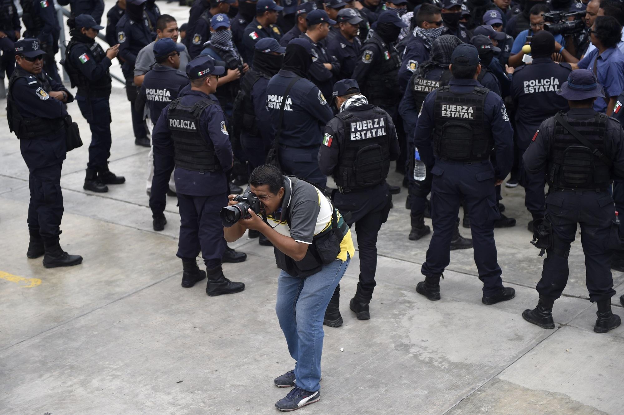 A Mexican photojournalist works during a protest of police officers in Chilpancingo, Guerrero state, Mexico, on May 30, 2017. In line with journalists murdered and disappeared in Mexico since the militarization of the war against drugs, there is an increasing and 
