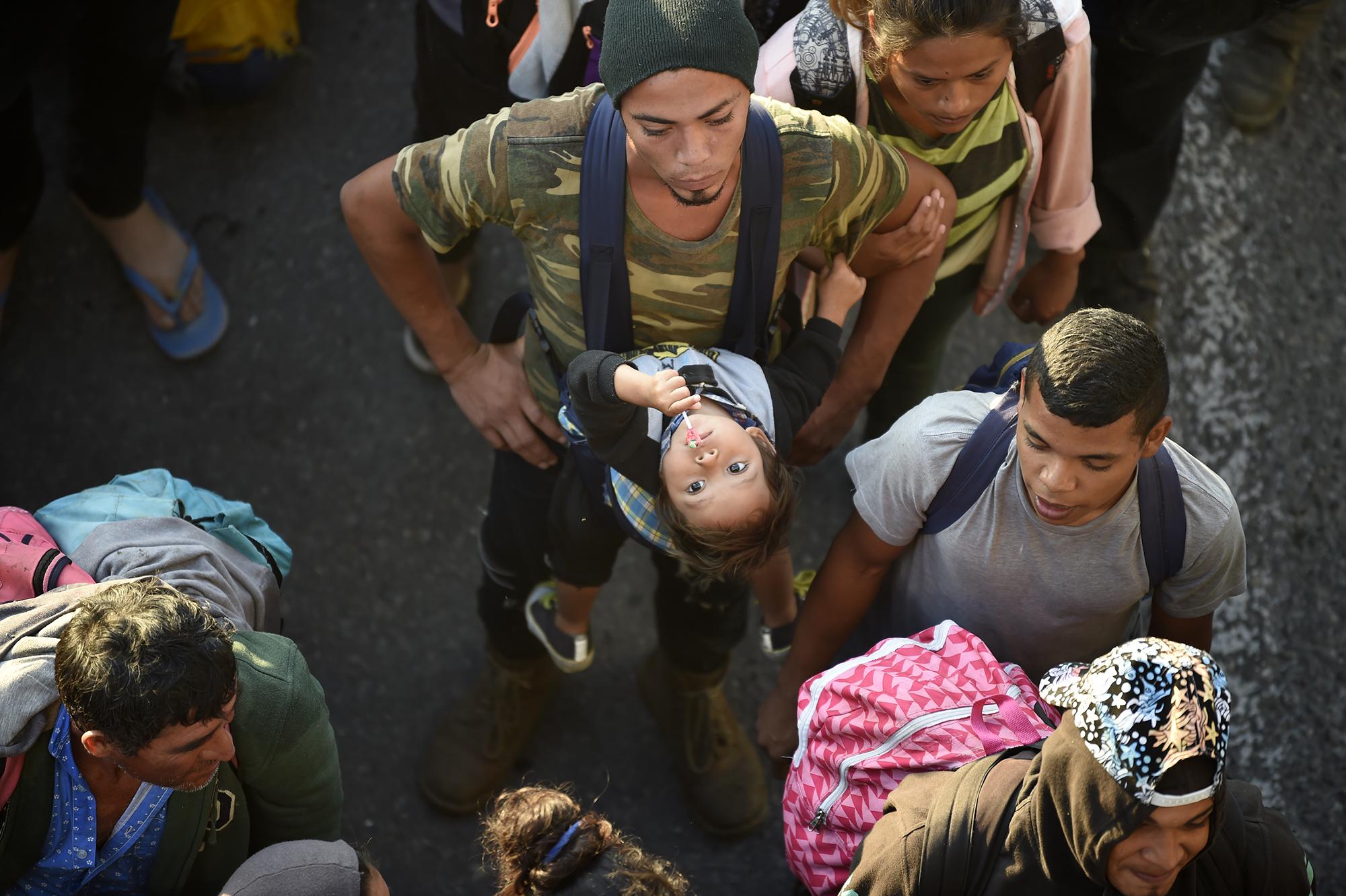 Un hombre carga a su hijo entre la multitud. Desde que la caravana cruzó el río y se introdujo a México, la escena de padres y madres con sus niños fue constante. Foto de AFP: Alfredo Estrella.