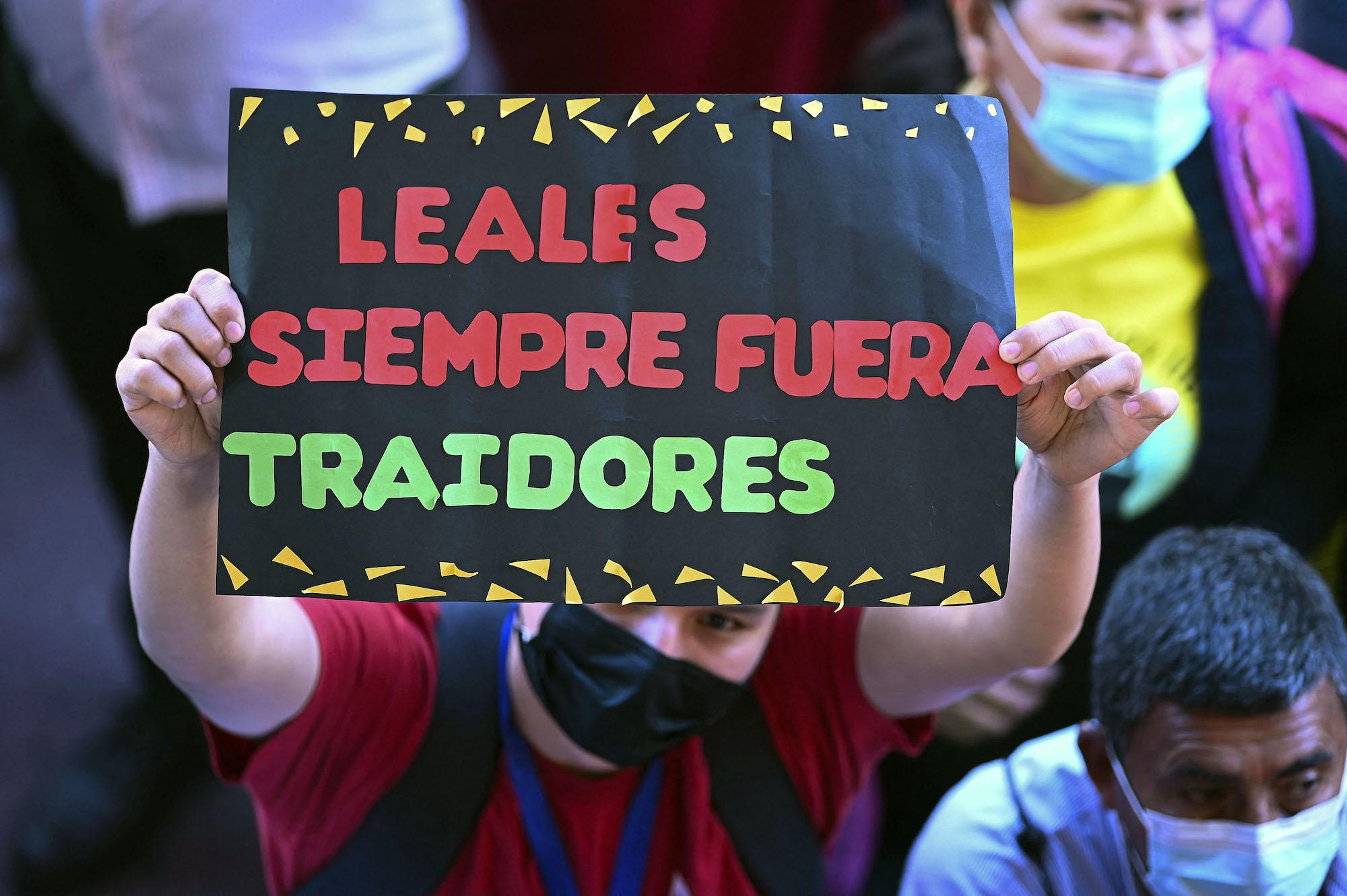 Un seguidor de Libertad y Refundacion (LIBRE) sostiene un cartel en apoyo al partido afuera del Congreso hondureño exigiendo que se respete el acuerdo preelectoral que daba la presidencia de ese órgano de Estado a Luis Redondo. Foto: Orlando Sierra / AFP.