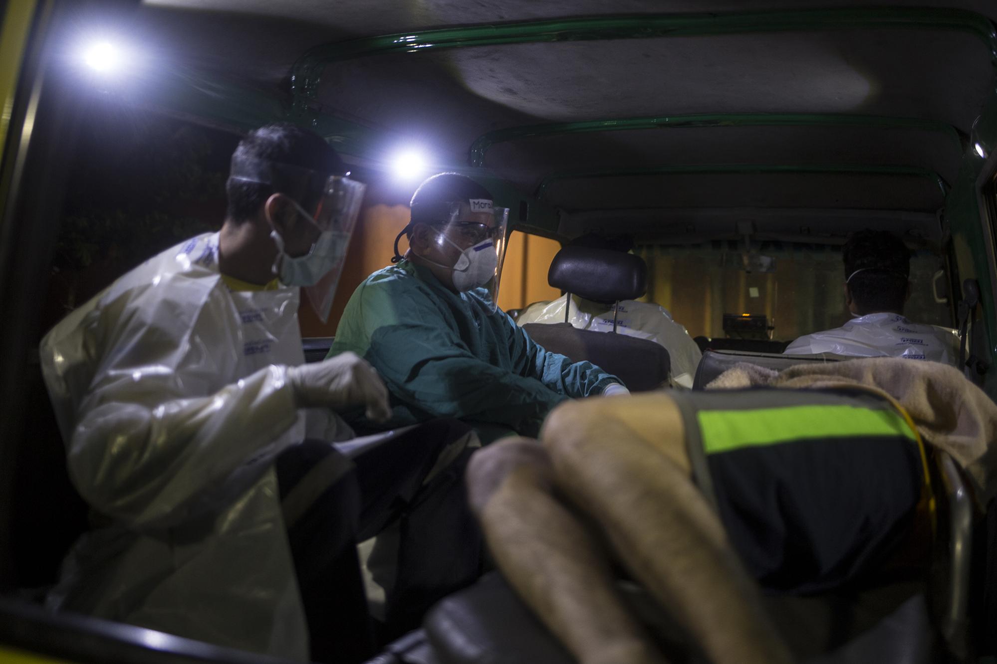 Miembros de Comandos de Salvamento atienden a un paciente, frente a la puerta de emergencia del hospital Rosales, la noche del 18 de mayo de 2020. Foto de El Faro: Víctor Peña. 