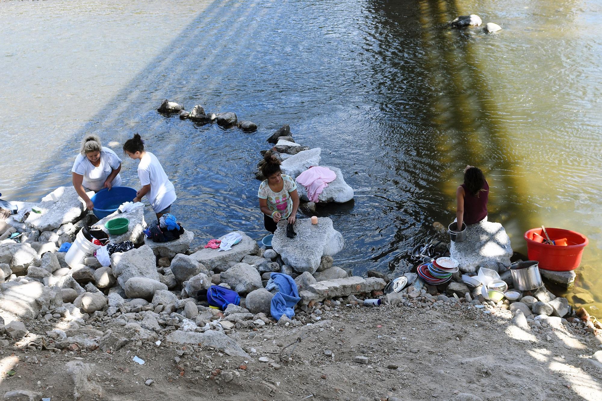 Mujeres lavan la ropa en el río Lempa a su paso por el municipio chalateco de Citalá. Usan productos de limpieza que a pequeña escala también deterioran la calidad de las aguas. Foto Marvin Recinos (AFP).