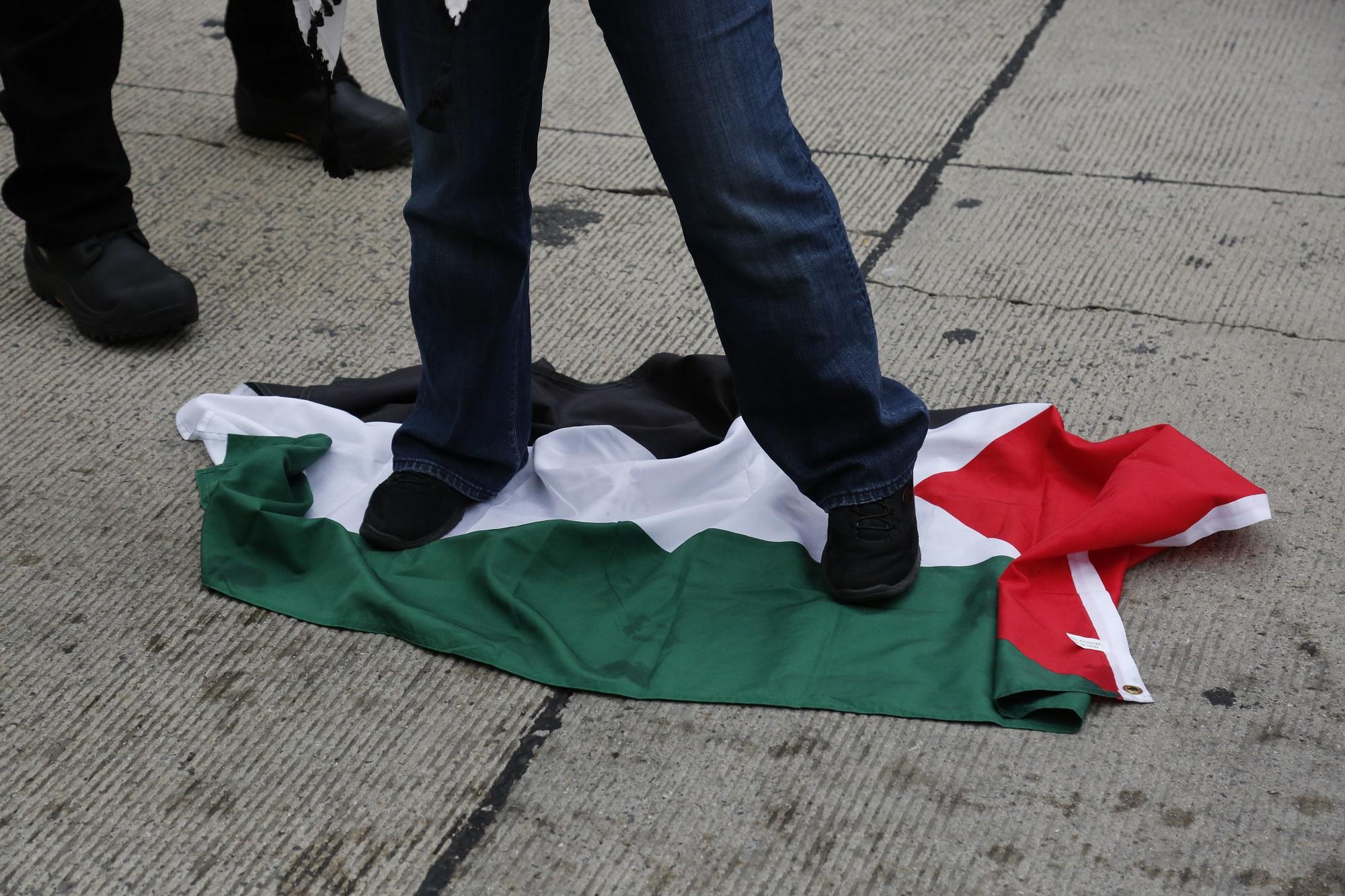Un seguidor de la Liga de Defensa Judía pisotea la bandera palestina. Foto Andrew Biraj (AFP).