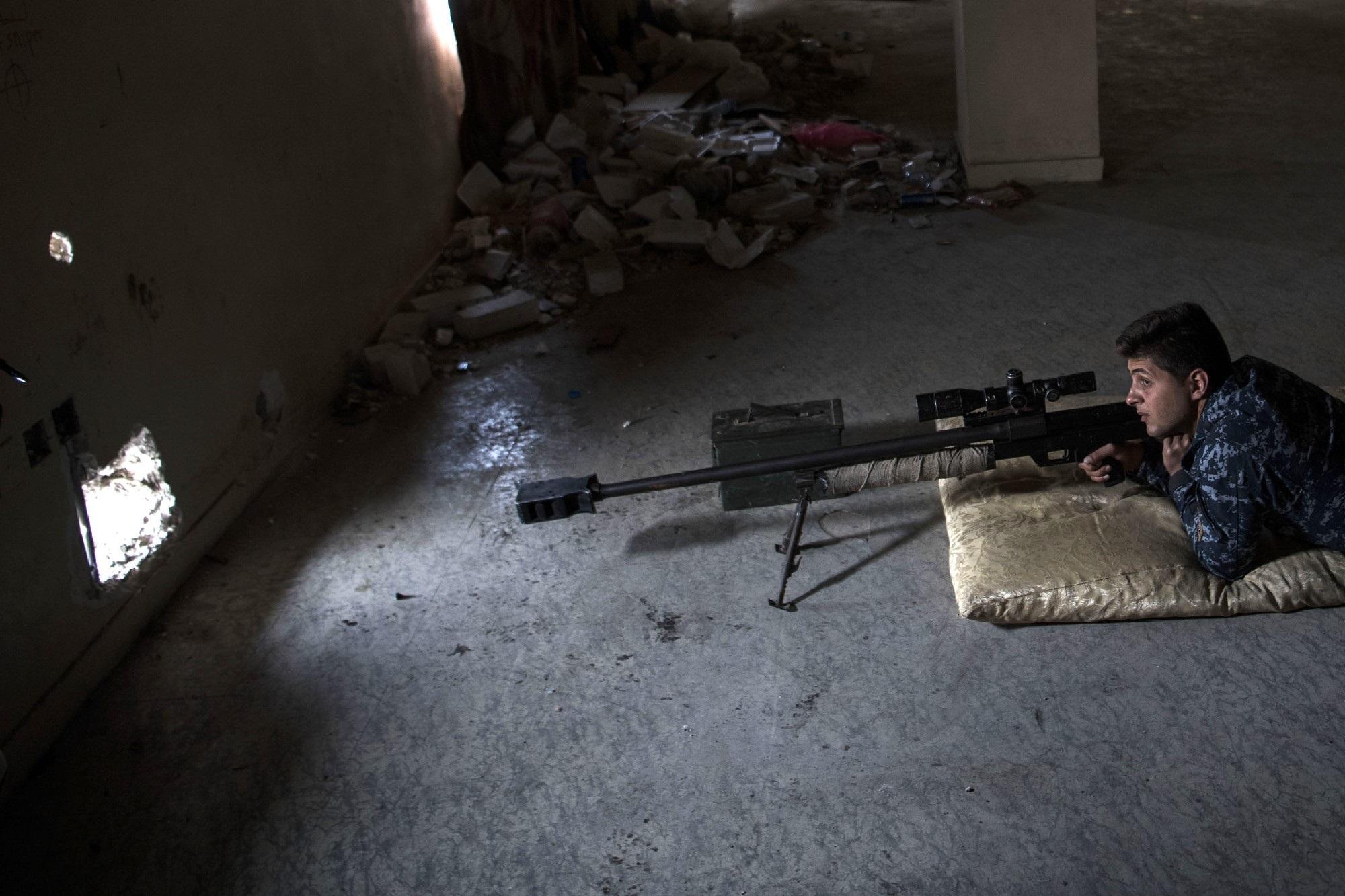 Un francotirador de la Policía Federal de Irak mantiene su posición en un edificio abandonado, desde el que trata de disparar contra supuestos militantes del grupo yihadista Estado Islámico. Foto Christophe Simon (AFP).