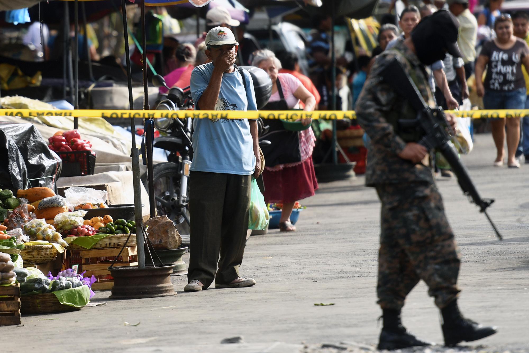 Un militar custodia la escena en la que yacen los cuerpos de cinco vendedores asesinados y un vigilante de seguridad, hecho ocurrido en el centro de San Salvador, el 15 de marzo de 2017.  / AFP PHOTO / Marvin RECINOS