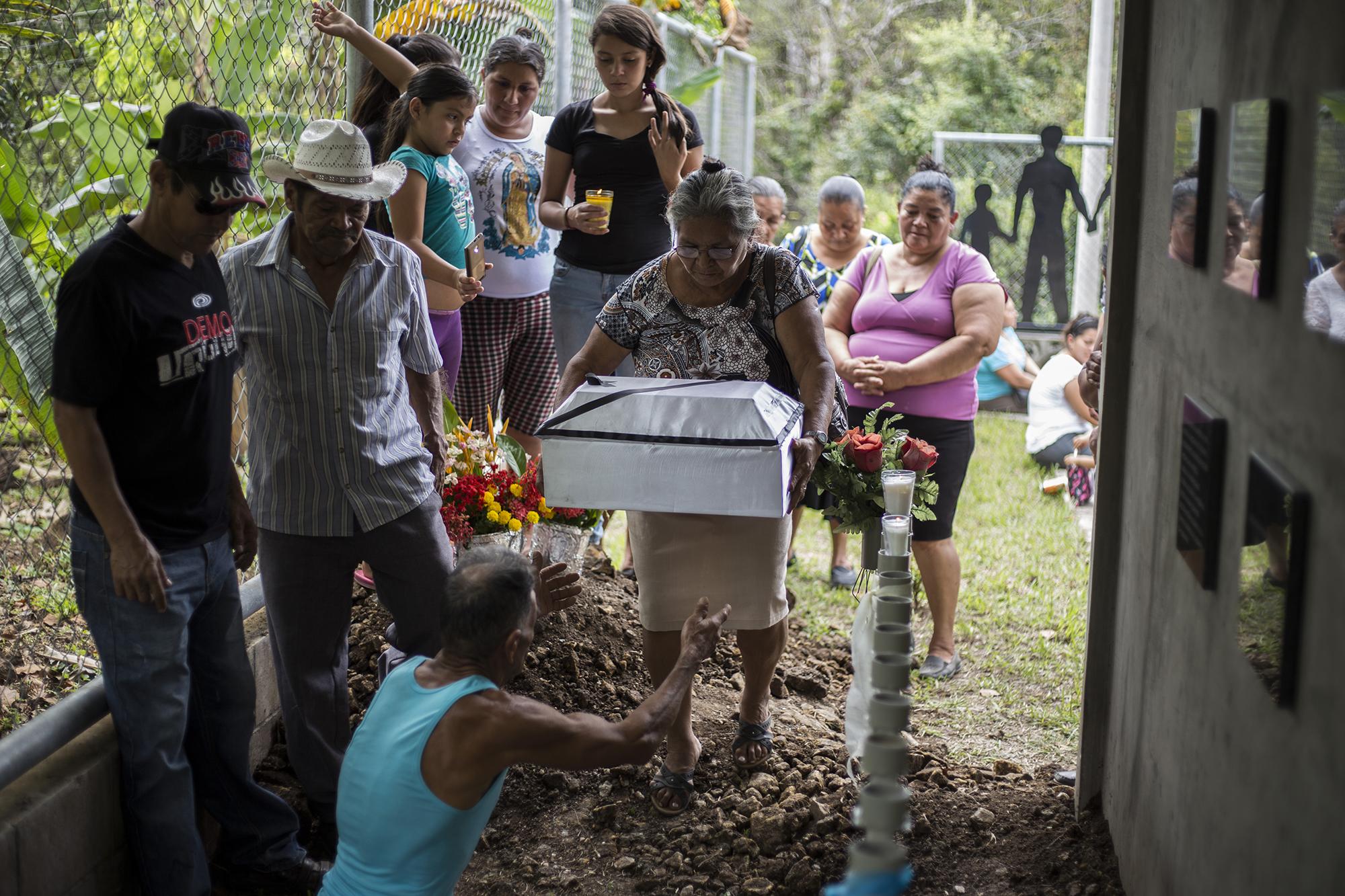 Rosario López entrega una de las seis osamentas a su esposo José de Los Ángeles Mejía, durante el sepelio, en el monumento a las víctimas de la masacre del cantón La Joya. Foto de El Faro, por Víctor Peña.