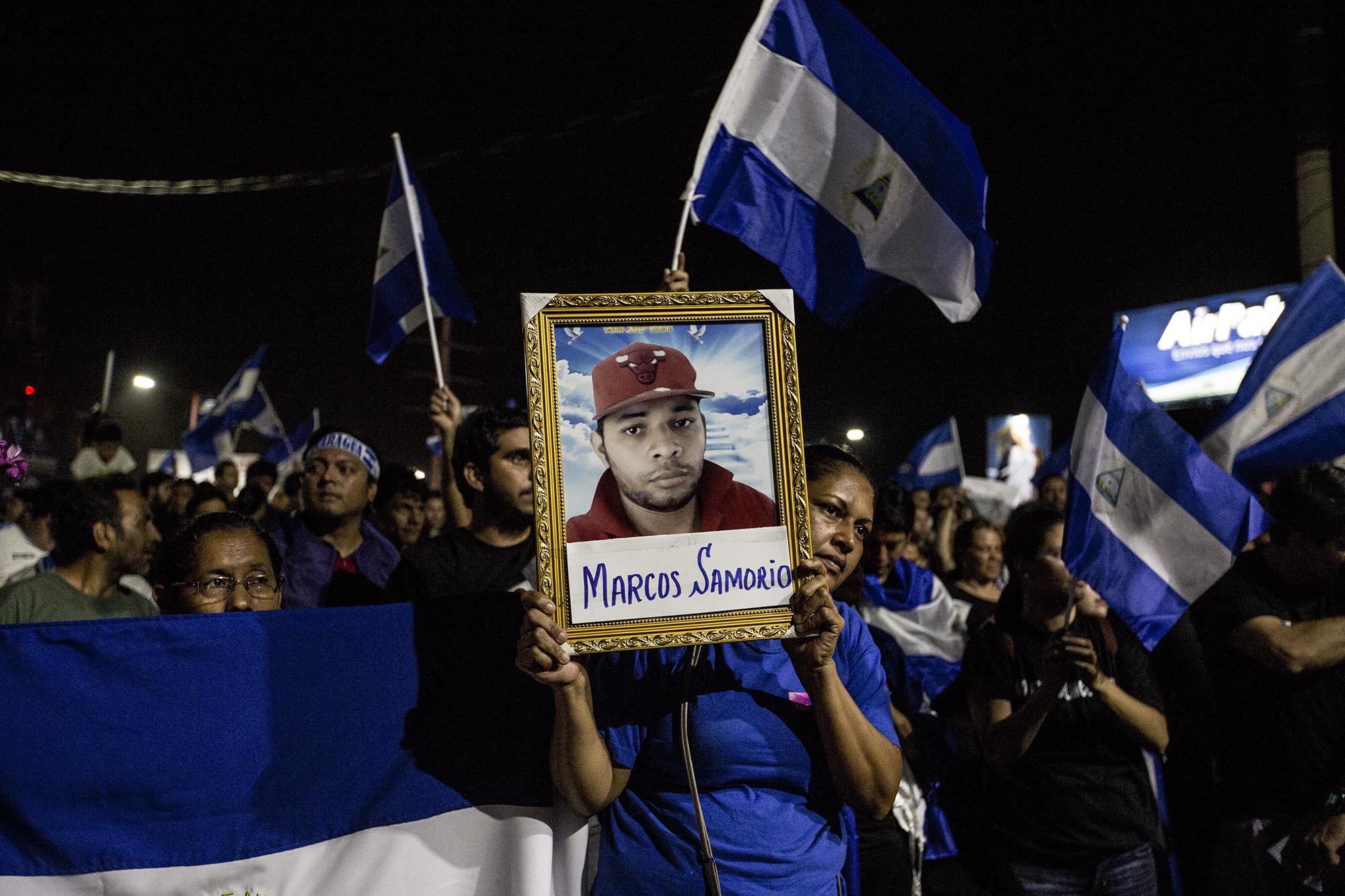 La tía de Marcos Samorio levanta un retrato de su sobrino, asesinado el 20 de abril por grupos de choque a favor del régimen de Daniel Ortega. Foto de Fred Ramos