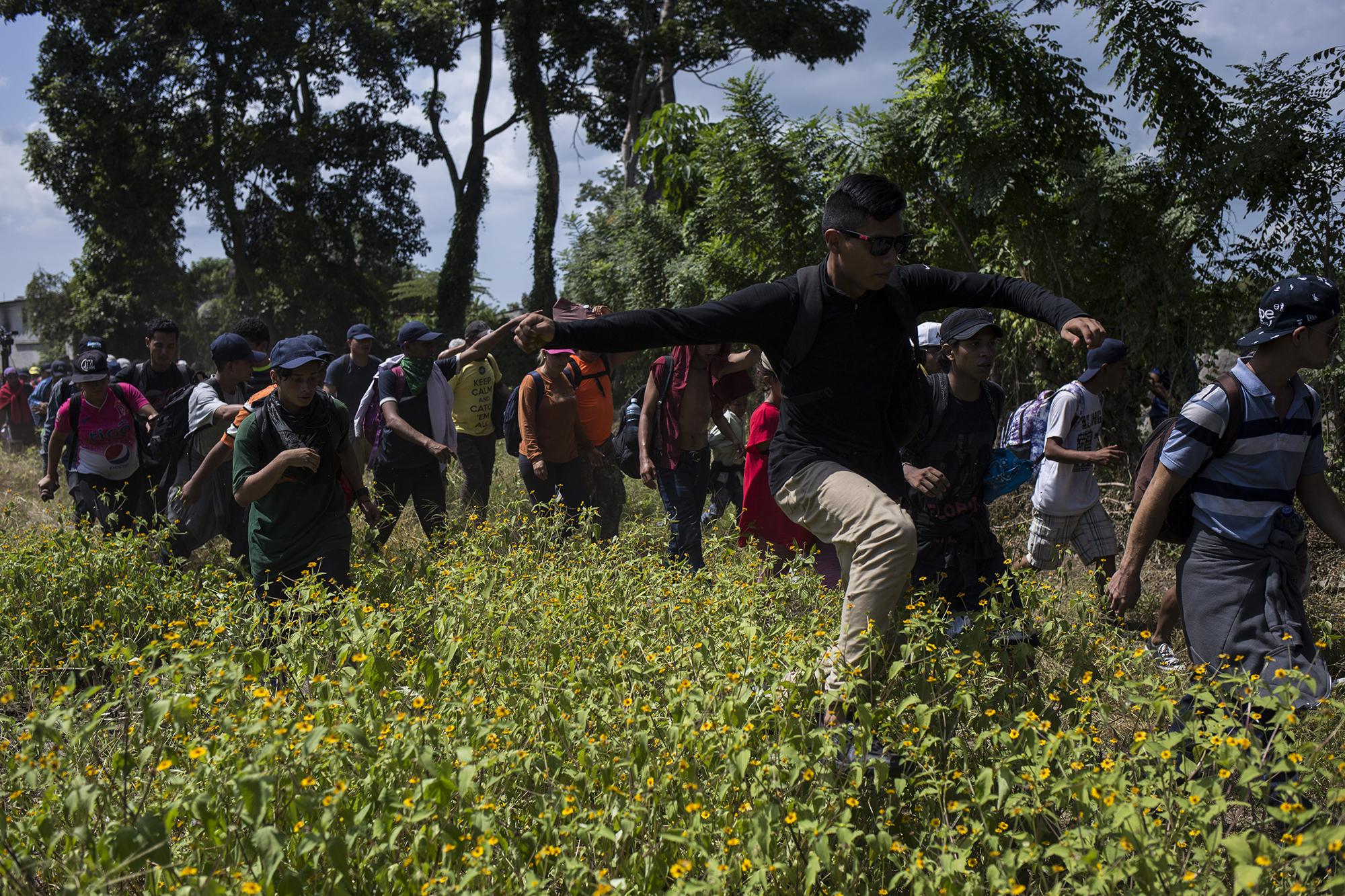 La caravana de migrantes salvadoreños camina sobre el monte para buscar un punto ciego donde cruzarse el río Suchiate, en la frontera entre Guatemala y México. Foto: Víctor Peña.
