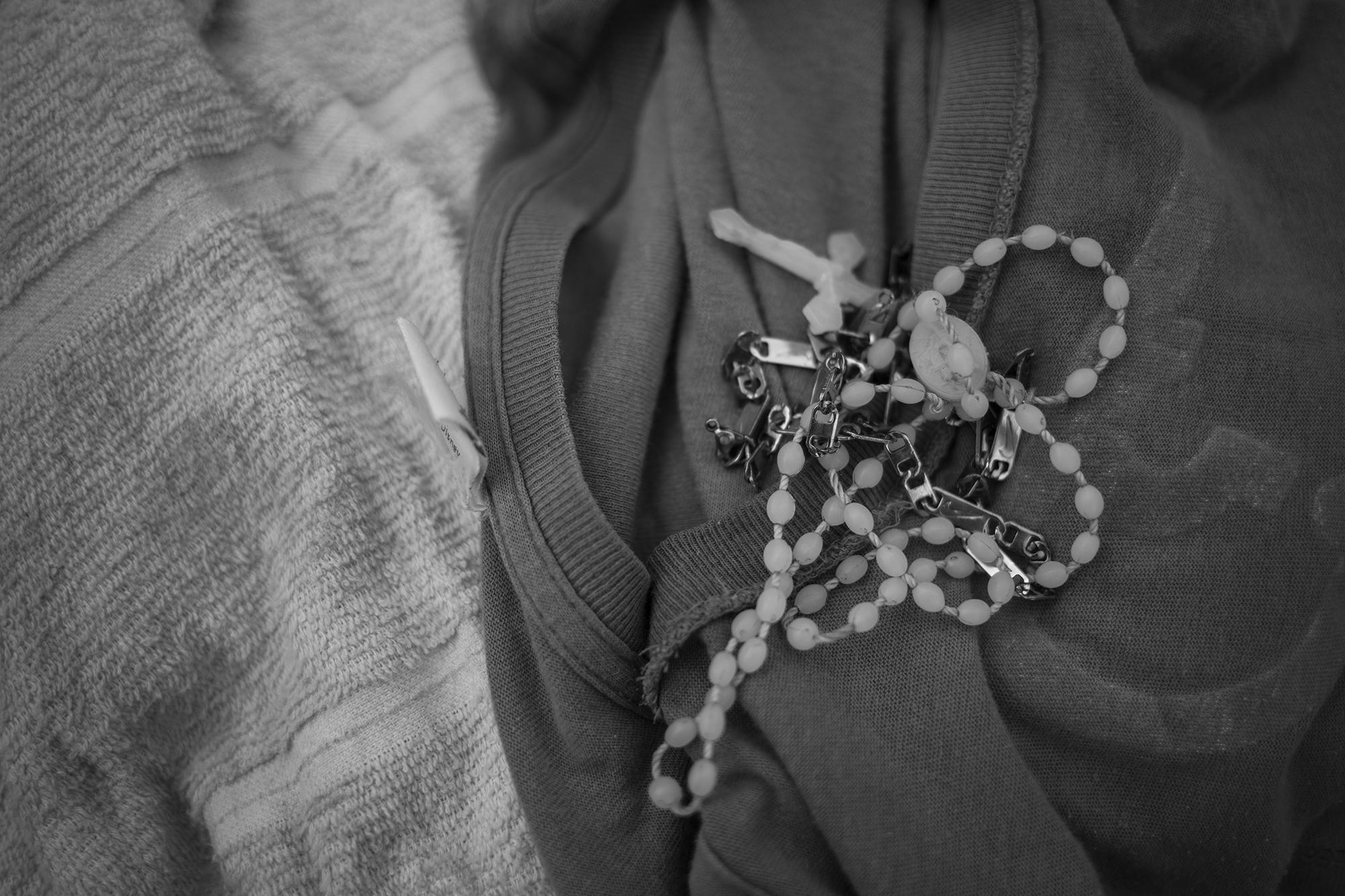 En su cuello carga dos amuletos: una cadena metálica y su camándula de plástico blanco. Cuida esas pertenencias como si fueran objetos de valor. 
