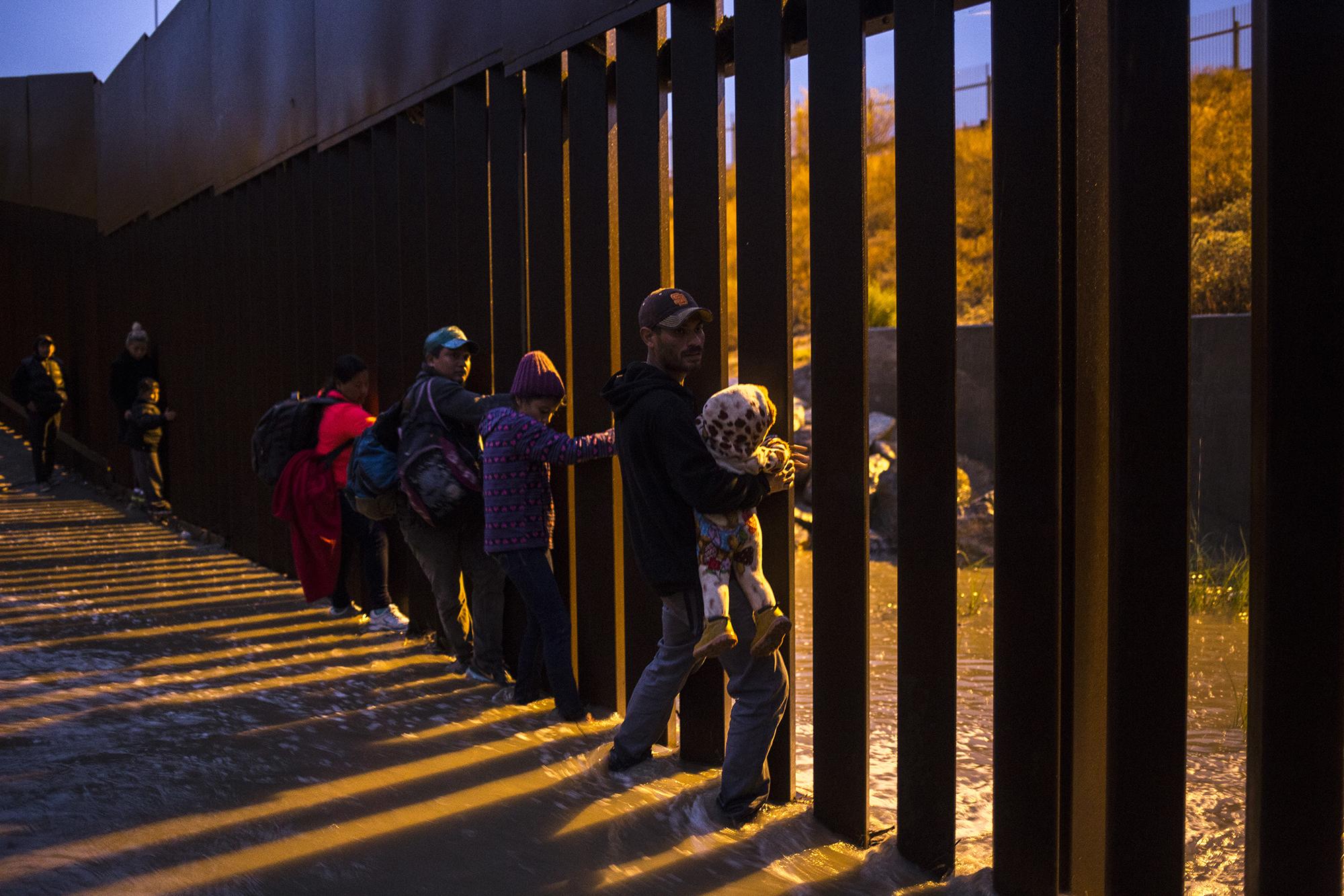 Padres desesperados, salvadoreños y hondureños con sus hijos en brazos, intentando cruzar el muro fronterizo en playas de Tijuana, México. Diciembre de 2018. Foto: Víctor Peña/ El Faro