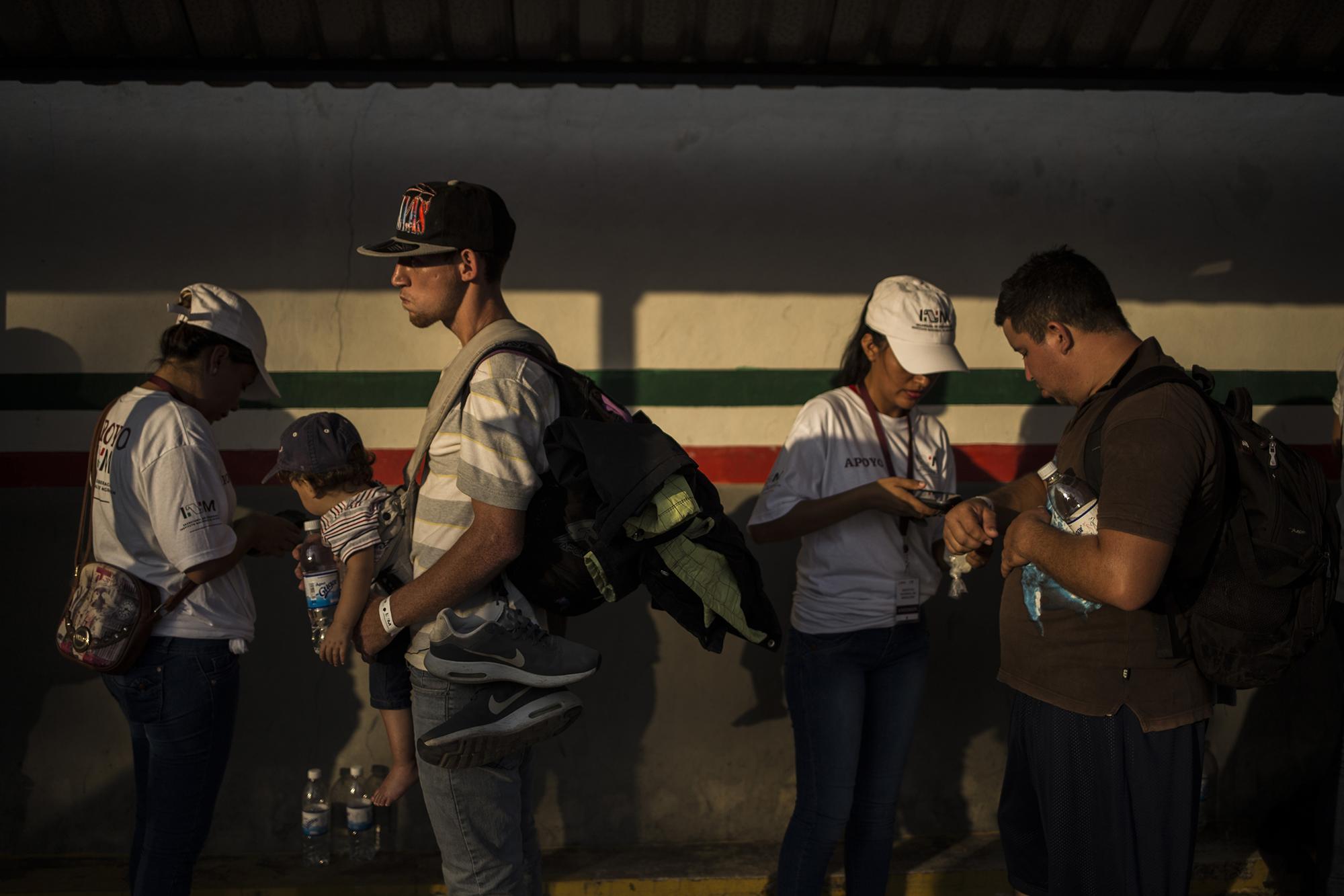 Equipo del Instituto Nacional de Migración de México coloca brazaletes a los migrantes que se han sometido al proceso de registro para obtener una visa humanitaria. En la frontera Tecún Umán los centroamericanos siguen llegando para someterse al proceso. Foto: Víctor Peña.