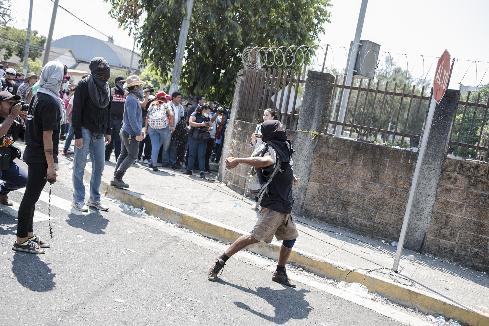 Un manifestante lanza una piedra hacia las ventanas de la Corte Suprema de Justicia. Otros también lanzaron a los policías de la UMO y a los carros de los empleados de la CSJ. Foto: Fred Ramos