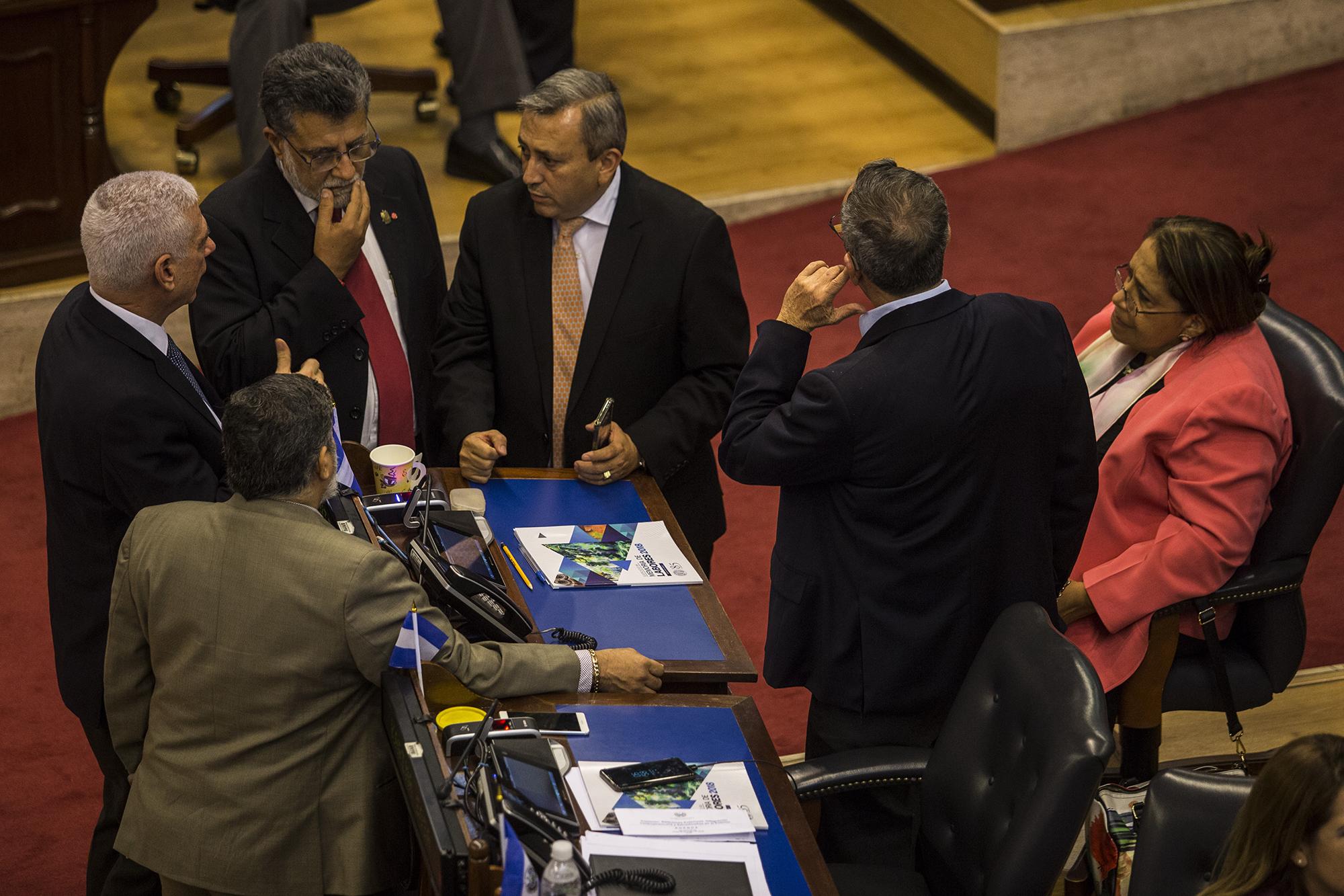 Los diputados Rodolfo Parker (PDC), Schafik Hándal (FMLN), Carlos Reyes (Arena), Roberto Angulo (PCN) y Nidia Díaz (FMLN) conversan durante la sesión plenaria del 23 de mayo de 2019. Los diputados de Arena y FMLN, en su mayoría, intentaron introducir una nueva ley de reconciliación. Foto: Víctor Peña.