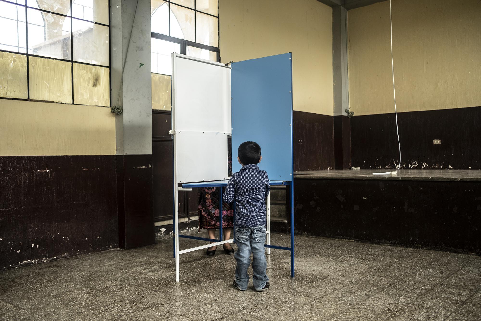 El niño José Antonio acompañó a su madre, Gloria Patzan, e imitó lo que ella hacía mientras ejercia el voto en el centro de votación Parroquia San Pedro Sacatepéquez.
