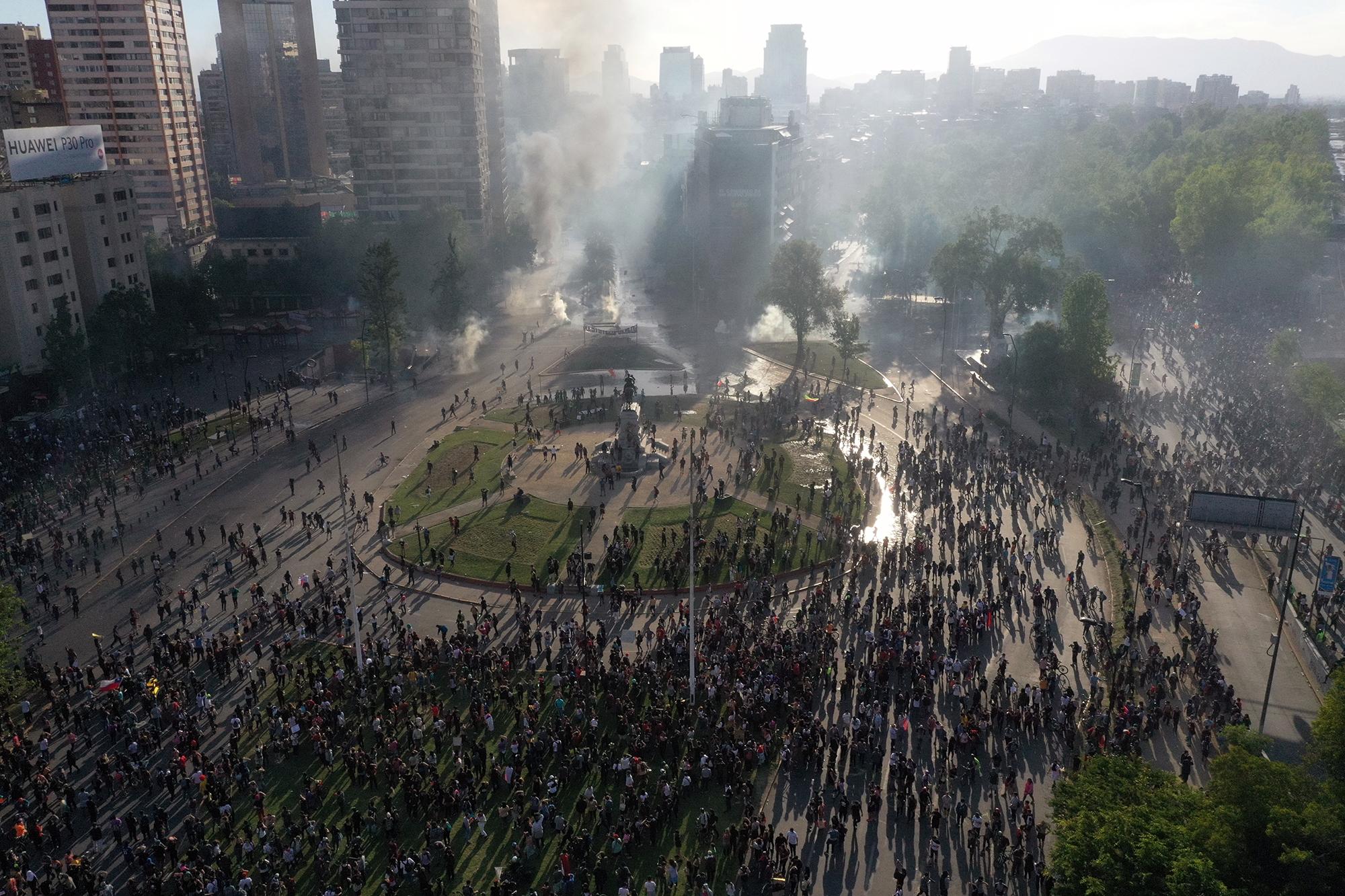 En esta vista aérea, los manifestantes chocan con la policía antidisturbios en la Plaza Italia en Santiago, Chile, el 21 de octubre de 2019. Las manifestaciones que iniciaron contra los precios de los boletos del metro, pero que degeneraron en un estallido social contra la clase política, continúan.  Foto por Pedro Ugarte / AFP.