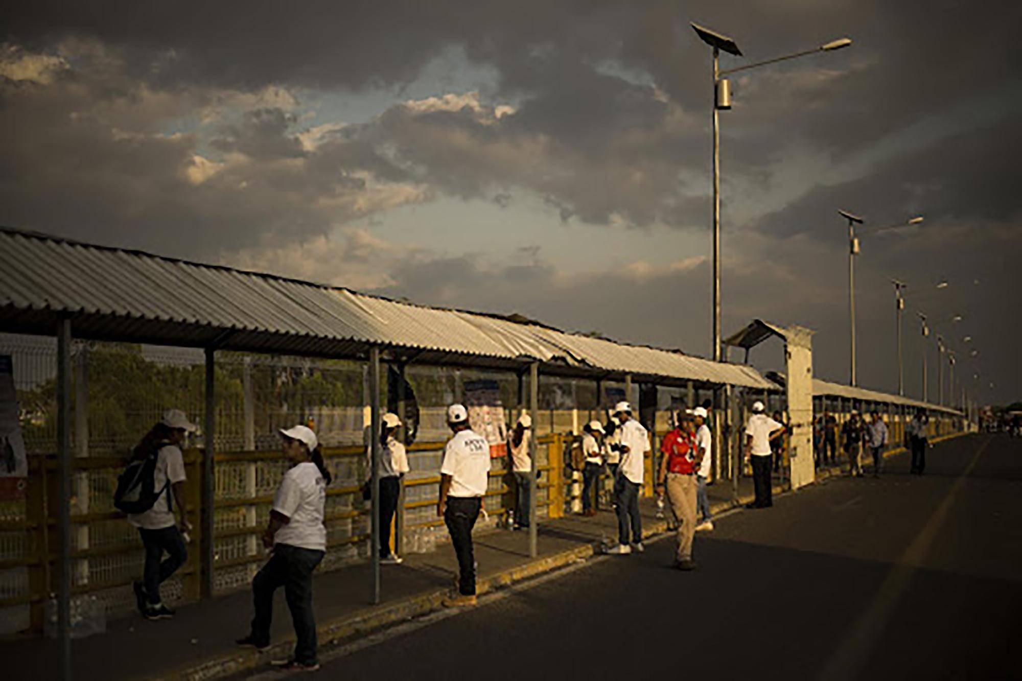 Team members from Mexico’s National Immigration Institute (INM) stand along the pedestrian path on the Rodolfo Robles bridge, which crosses the Suchiate River that divides Guatemala and Mexico. Since January 17, 2019, Mexico has opened its doors to Central Americans fleeing their home countries, offering them permits to travel and work freely in Mexican territory for up to one year.