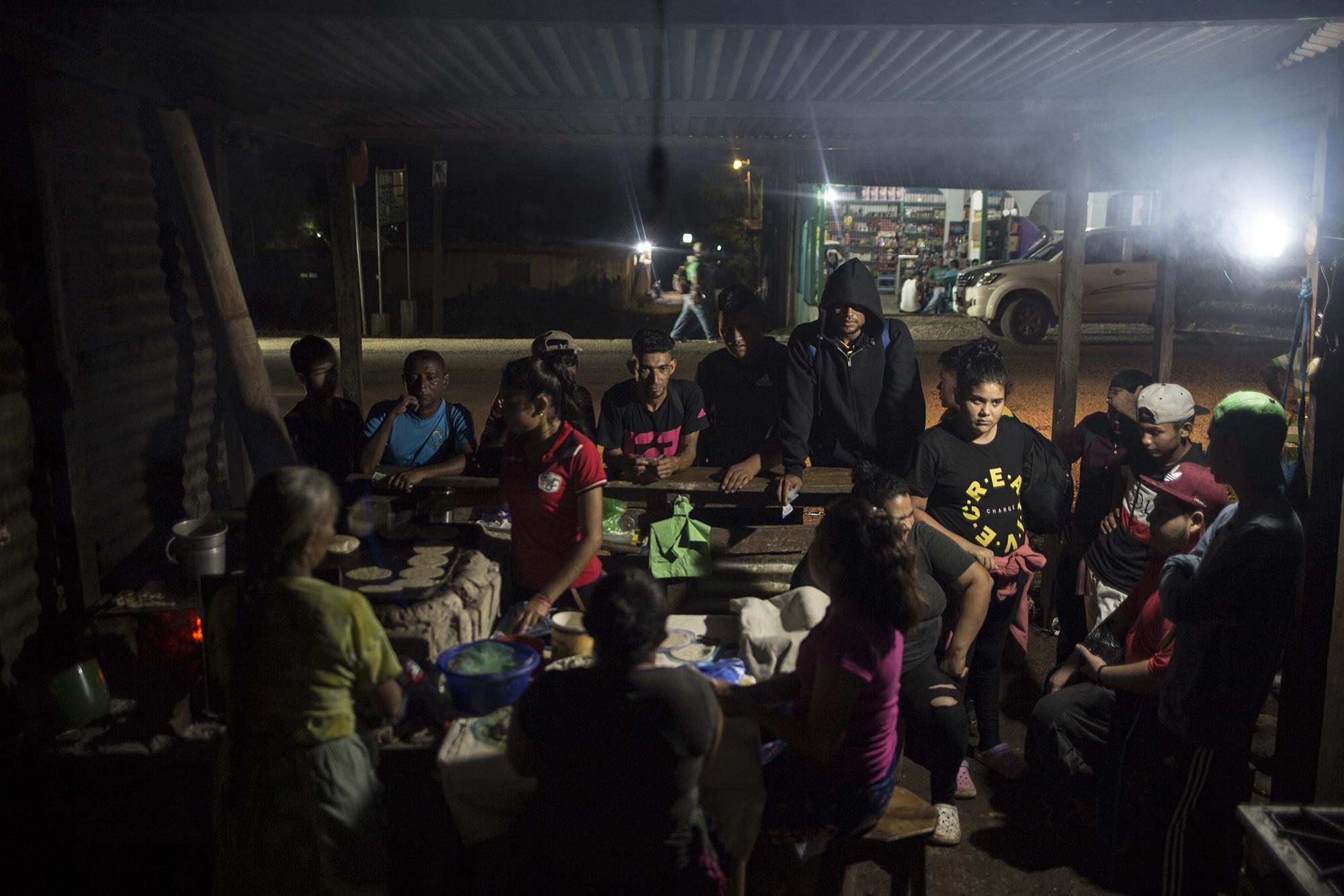 Algunos migrantes esperan para poder comprar tortillas para cenar, durante la noche del viernes 17 de enero. El poblado de El Ceibo (Guatemala) no está acostumbrado a recibir grandes números de migrantes: no cuenta con muchos hospedajes ni comedores y la electricidad se suspende desde las diez de la noche hasta la cinco de la madrugada.