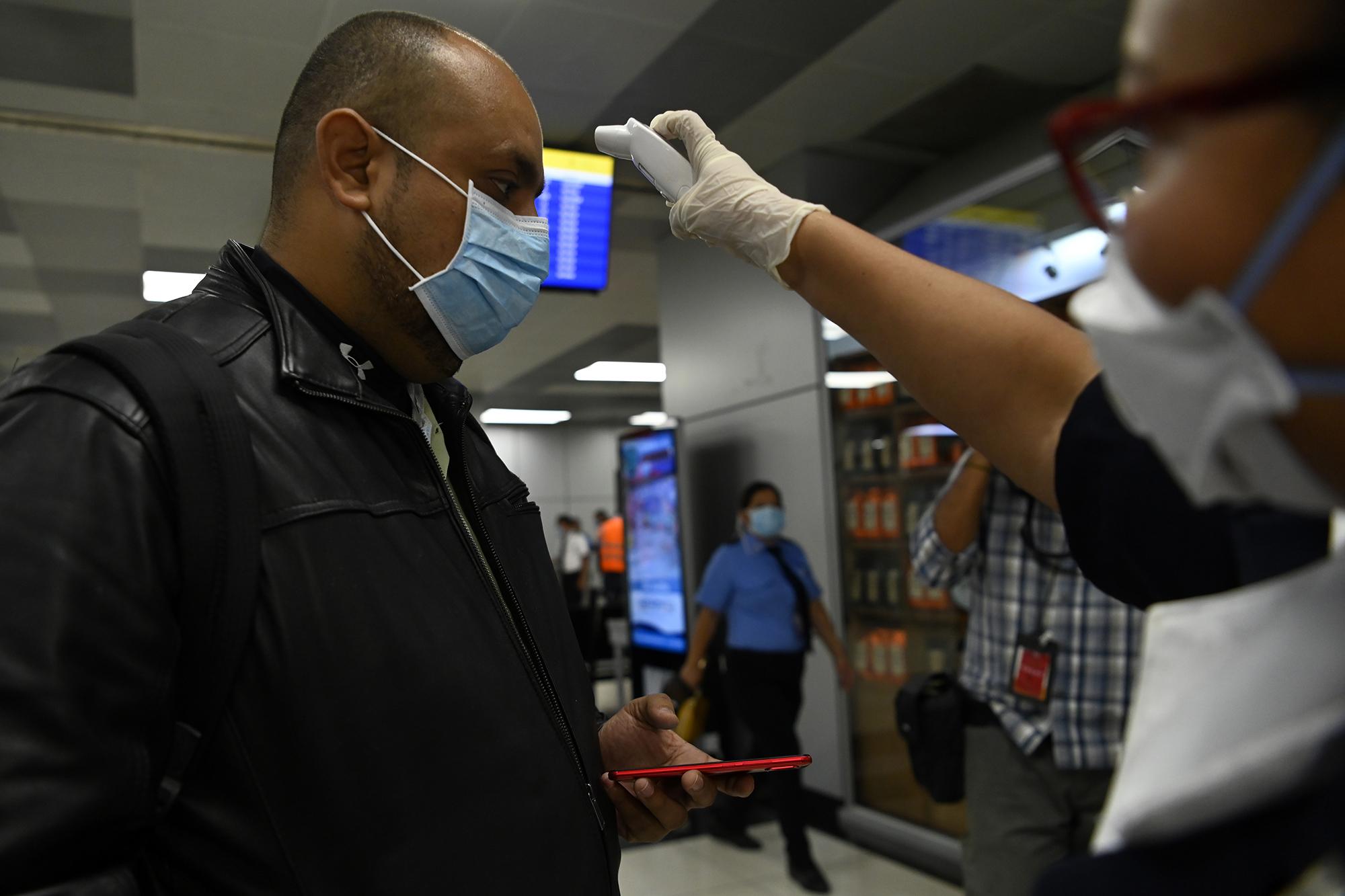 A passenger at El Salvador’s international airport gets his temperature checked while wearing a mask to protect against the coronavirus on March 12, 2020. Photo by Marvin Recinos/AFP