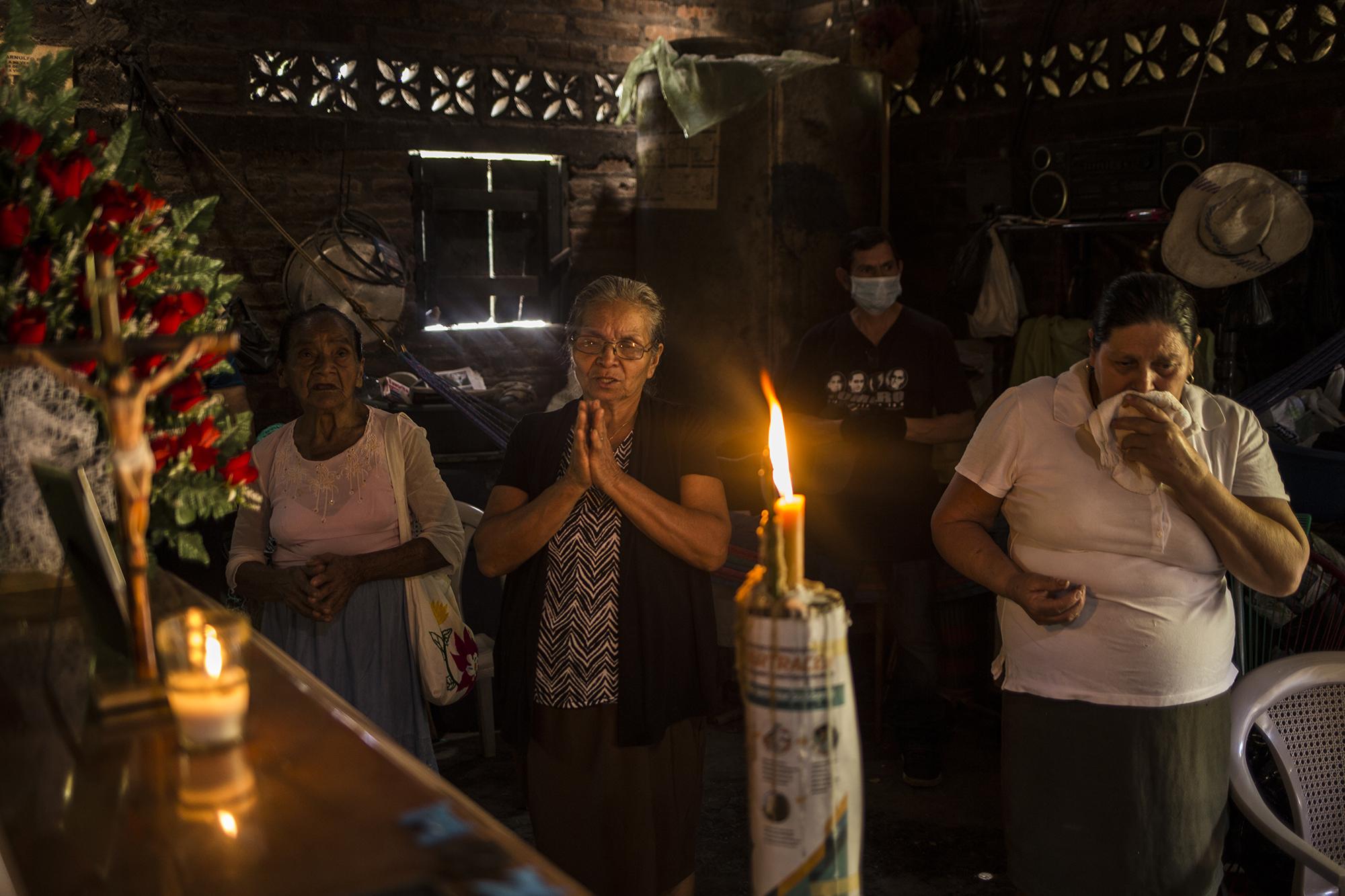 Rosario López (center), 72 years old, prays together with the few family members who were able to attend the funeral of her husband, Ángel Mejía, on March 24. Photo for El Faro: Victor Peña