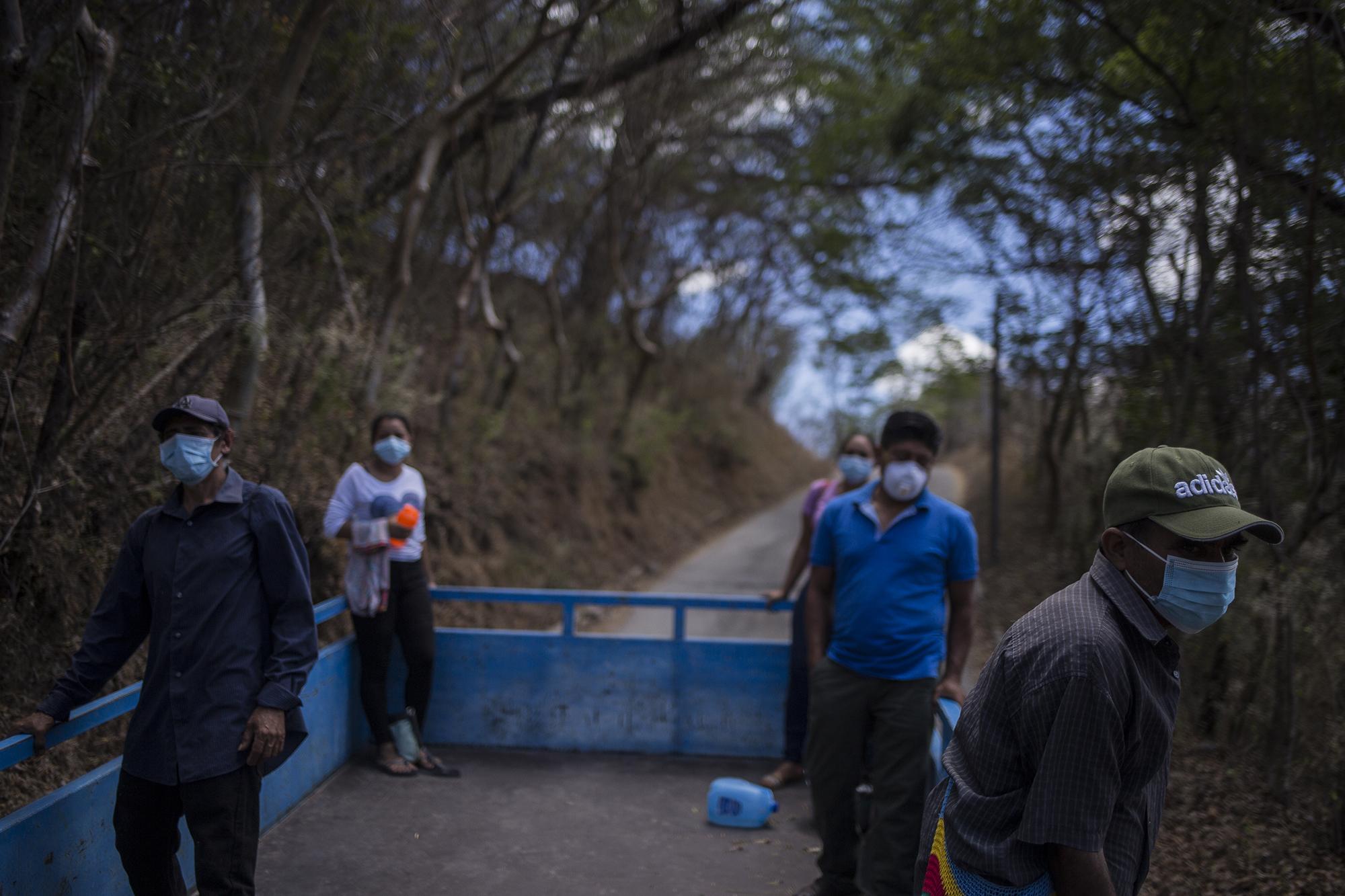 Ángel Mejía’s relatives ride in the back of a cargo truck. Three men and three women stand more than six feet apart as they head toward the Meanguera cemetery, in Morazán. They’re attending the funeral under new rules established one day earlier by the police in response to the COVID-19 emergency. Photo for El Faro: Víctor Peña.