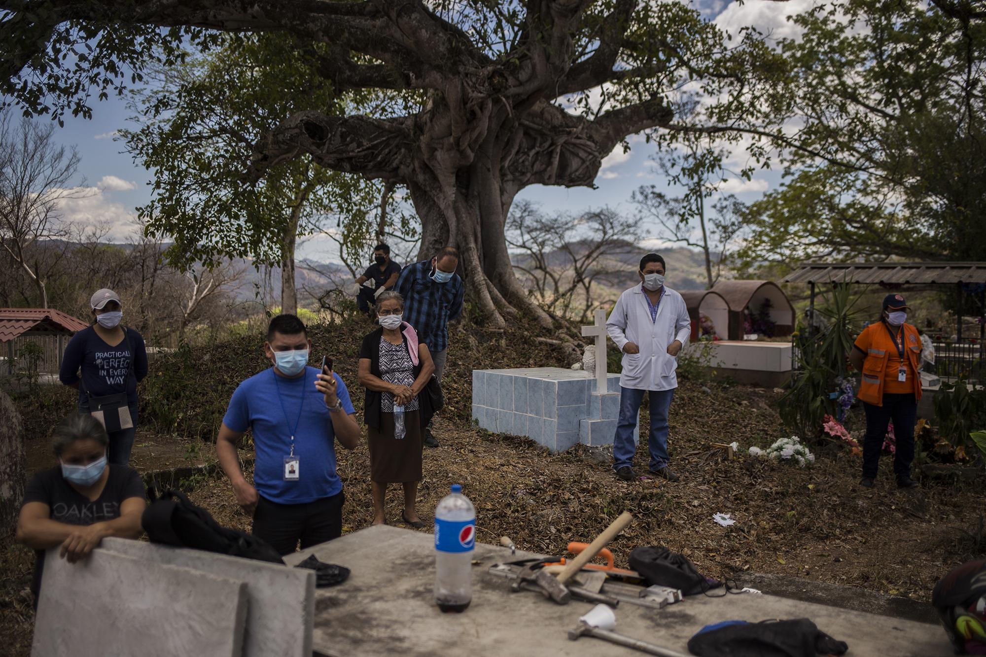 Representatives from the Municipal Commission of Civil Protection for the municipality of Meanguera attend Ángel Mejía’s burial, ensuring that the gathering is not in violation of the new pandemic health protocols that put limitations on public assemblies. Photo for El Faro: Víctor Peña.