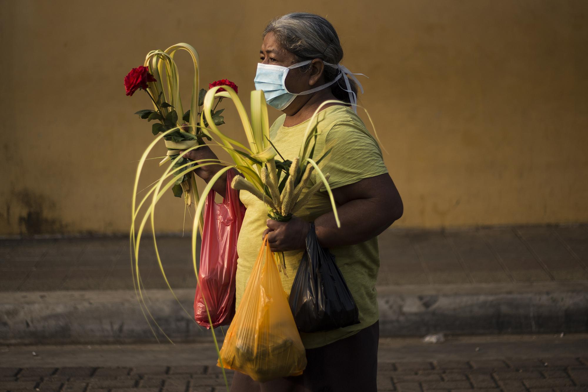 María Cristina, de 61 años, sale del mercado con alimentos y dos ramos para adornar su casa.