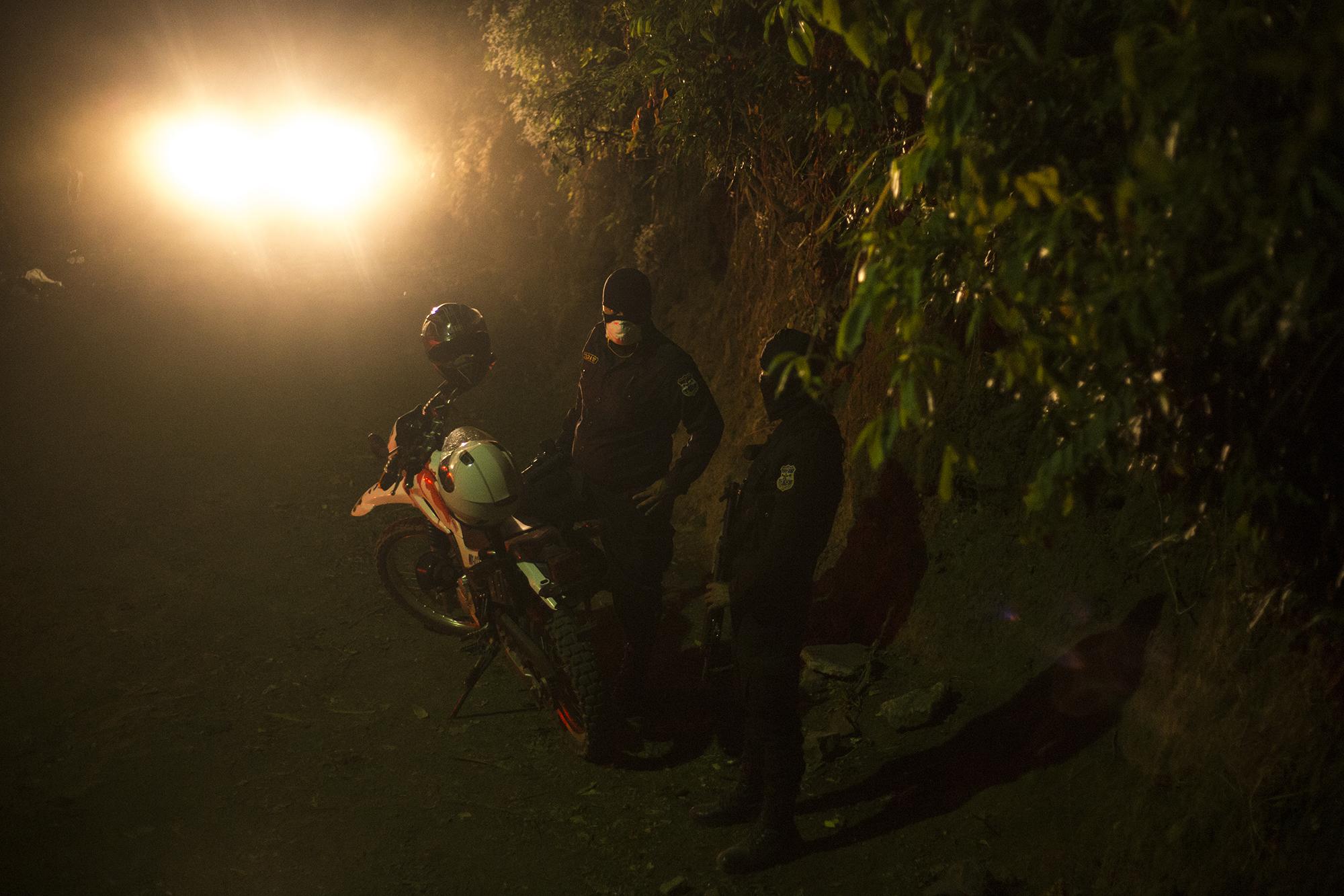 Agentes de la Policía Nacional Civil, custodian la escena de un feminicidio, en el cantón Casa de Piedra, del municipio de Panchimalco, la noche del martes 7 de abril de 2020. Foto de El Faro: Víctor Peña. 