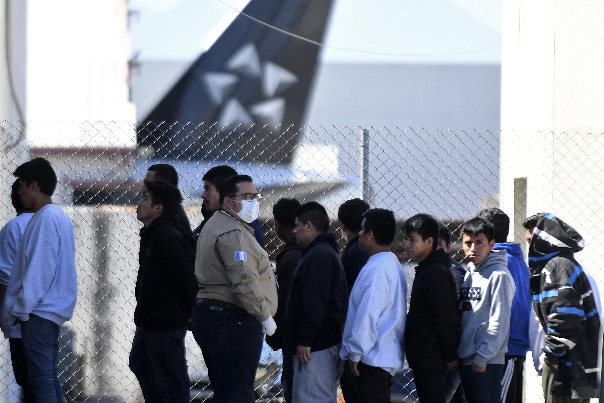 An immigration official uses a protective face mask as a preventive measure against the new coronavirus, COVID-19, upon the arrival of Guatemalan migrants deported from the United States, at the Air Force base in Guatemala City, on March 12, 2020. (Photo by Johan ORDONEZ / AFP)