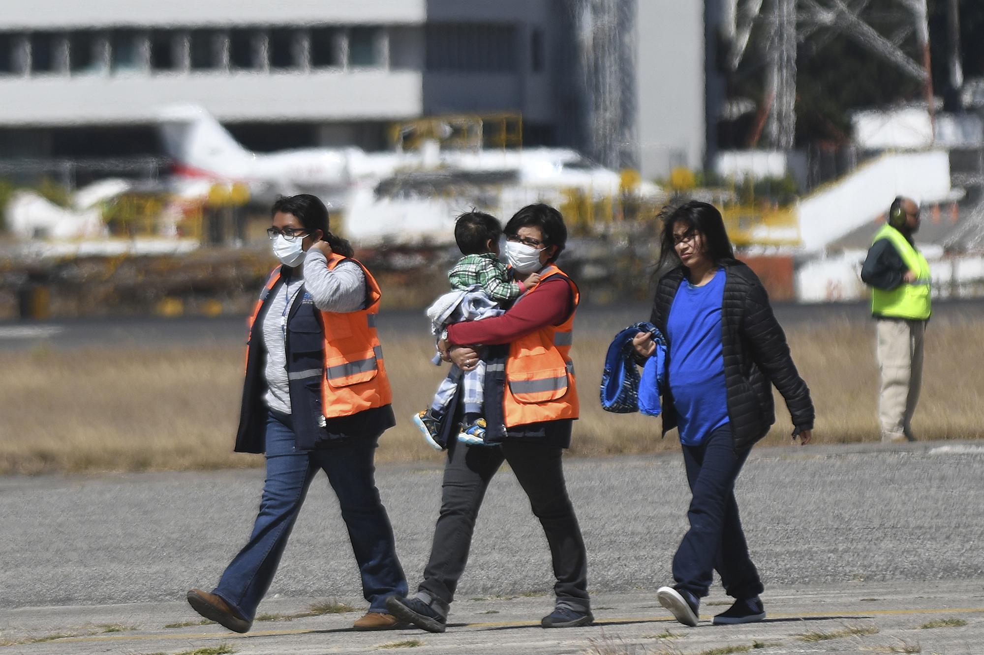 Guatemalan immigration officials use protective equipment as a preventive measure against the new coronavirus, COVID-19, as they receiving Guatemalan migrants deported from the United States, at the Air Force base in Guatemala City, on March 12, 2020. (Photo by Johan ORDONEZ / AFP)