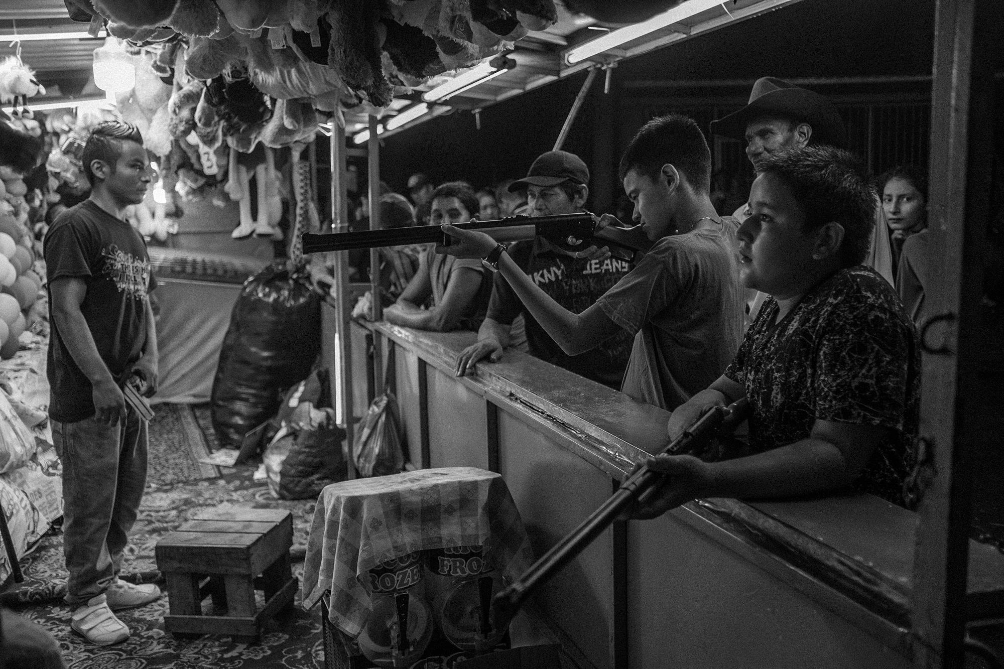 Youth from Santa Marta play a target shooting game during the festival of the return. One dollar buys three shots at hitting the target with a toy gun. The prize: a stuffed teddy bear.