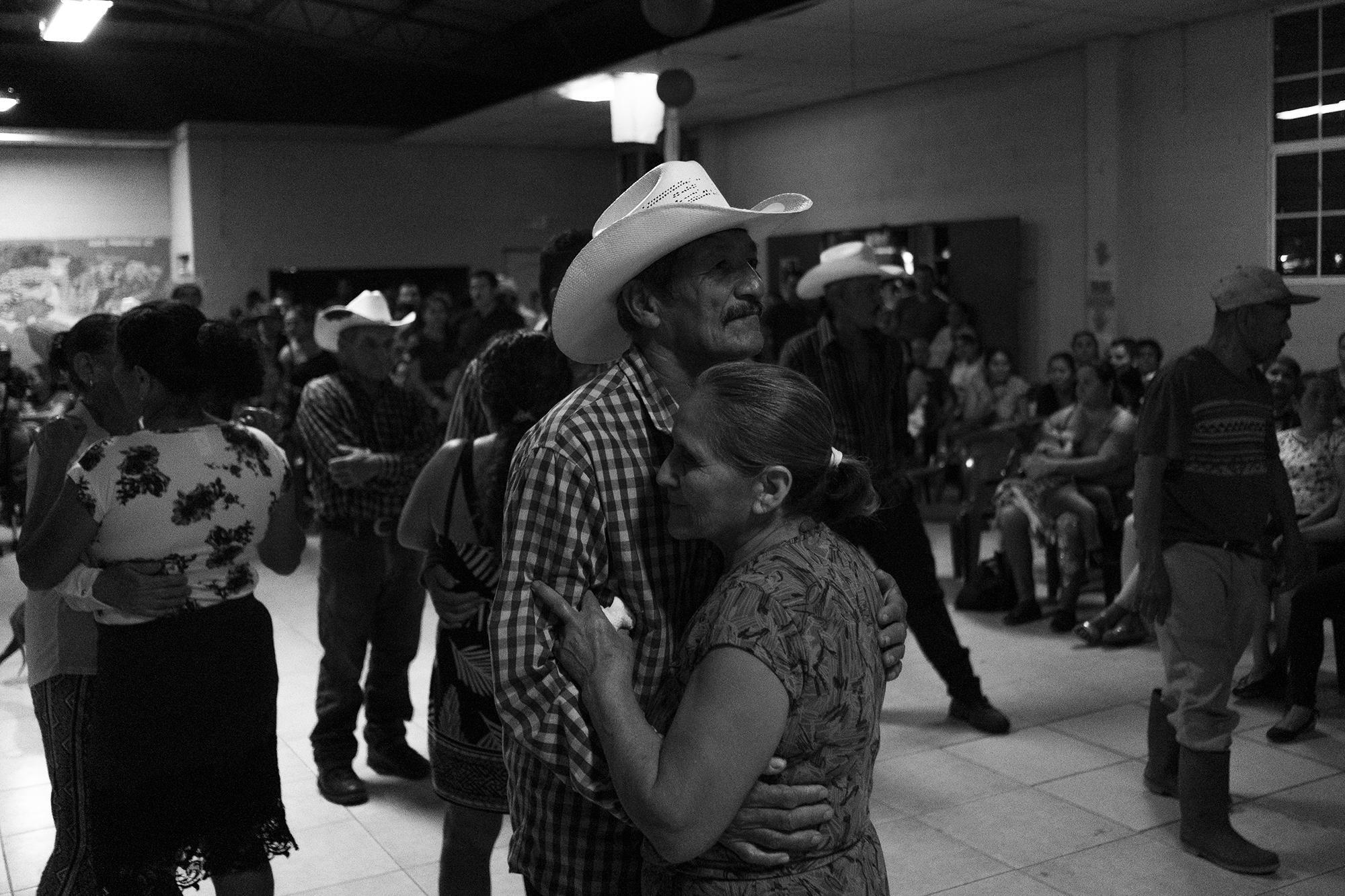 Gerardo Leiva and his wife, Dolores, hold each other as they dance to banda music during the celebration for community elders. 38 years ago, Dolores held on to her husband as they crossed the Lempa River to escape the Salvadoran Army.