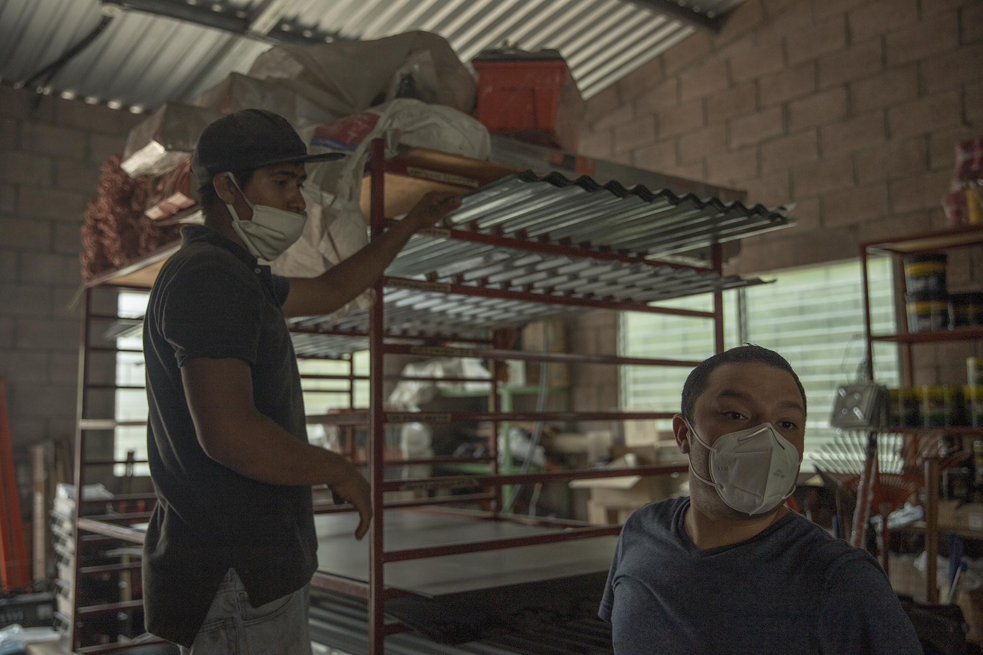 Dino Safie, right, in a hardware store in Verapaz, San Vicente, where he bought sheets of metal and cement blocks to help build a house for a woman in rural Verapaz. Photo: Carlos Barrera/El Faro